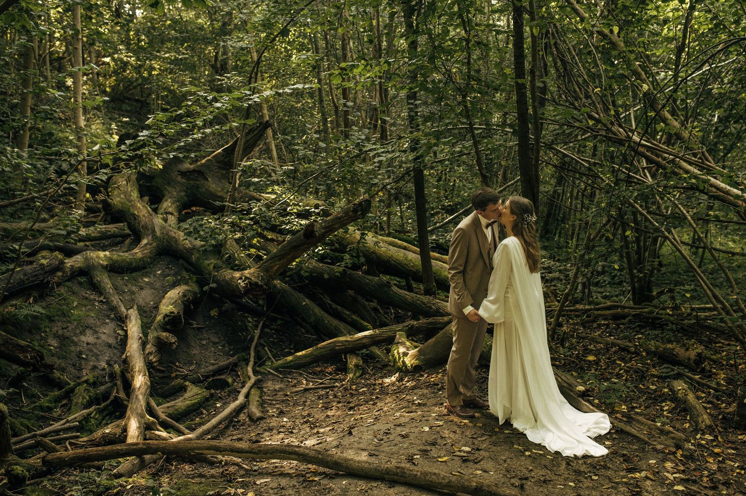 A figure in a flowing white dress walks through a mystical forest setting with moss-covered trees and filtered sunlight.