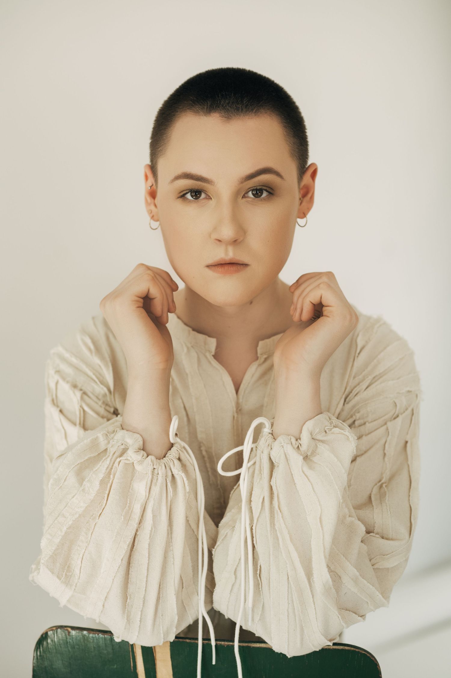Studio portrait in cream colored ruffled top with minimalist lighting and styling.