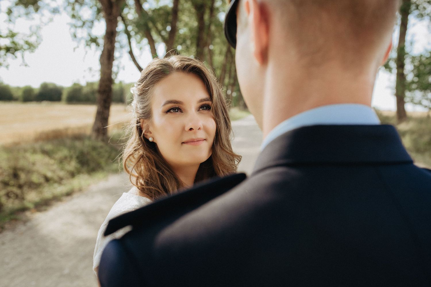 Intimate wedding moment captured on a tree-lined path during golden hour.