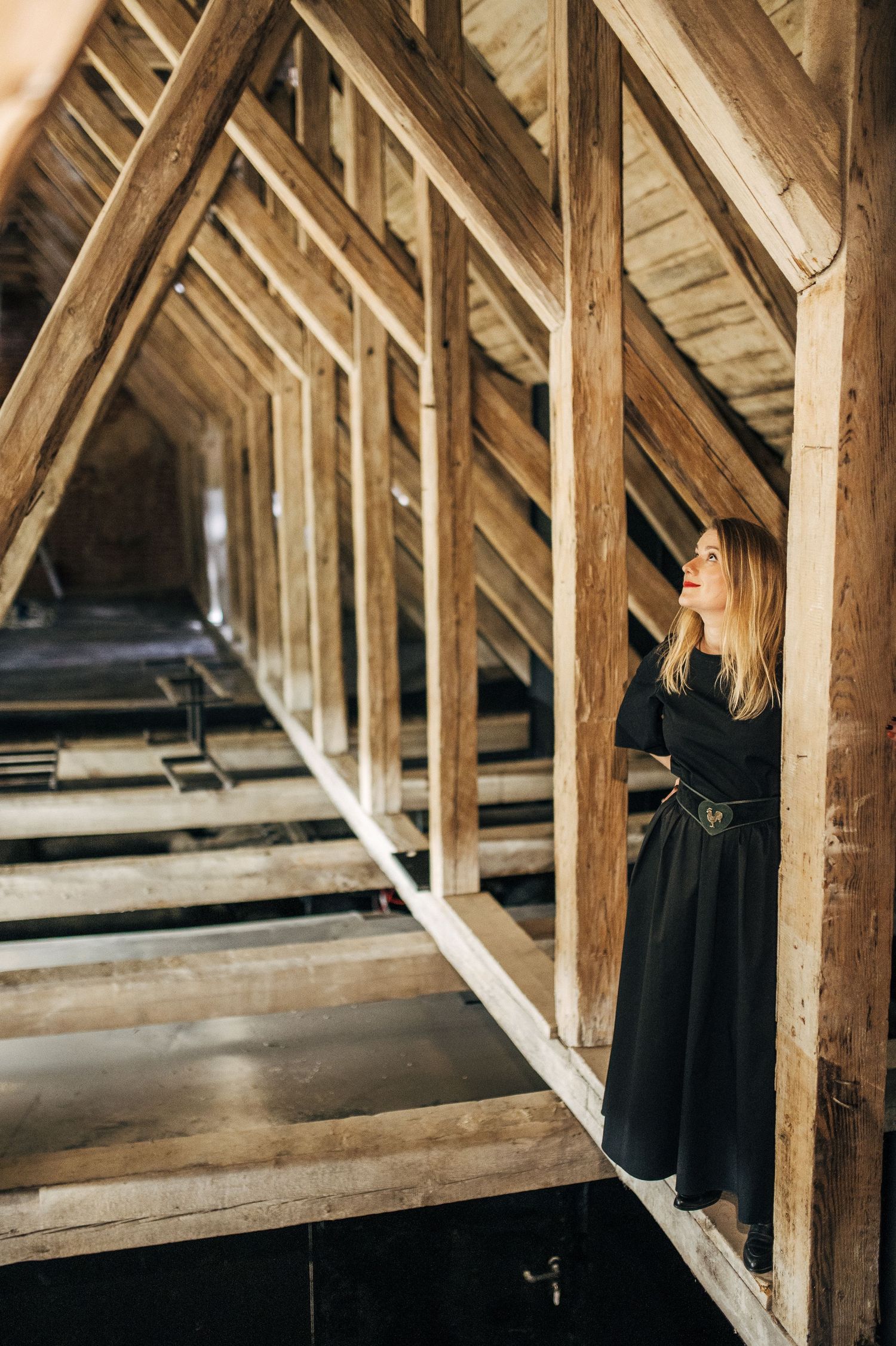 Atmospheric wooden beams and rafters of an attic space create geometric patterns in natural light.