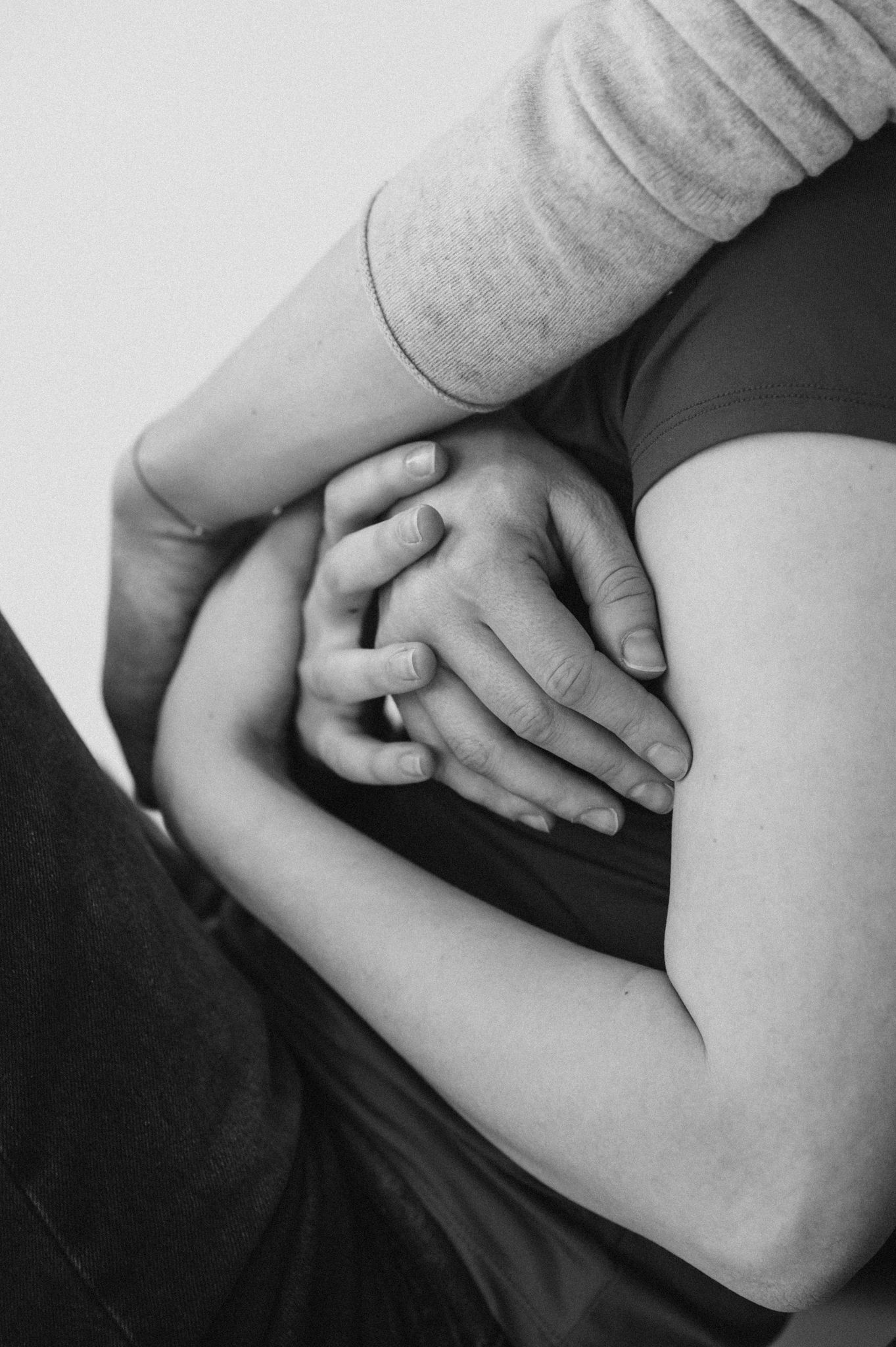 Series of gentle black and white photographs showing hands resting on a pregnant belly.