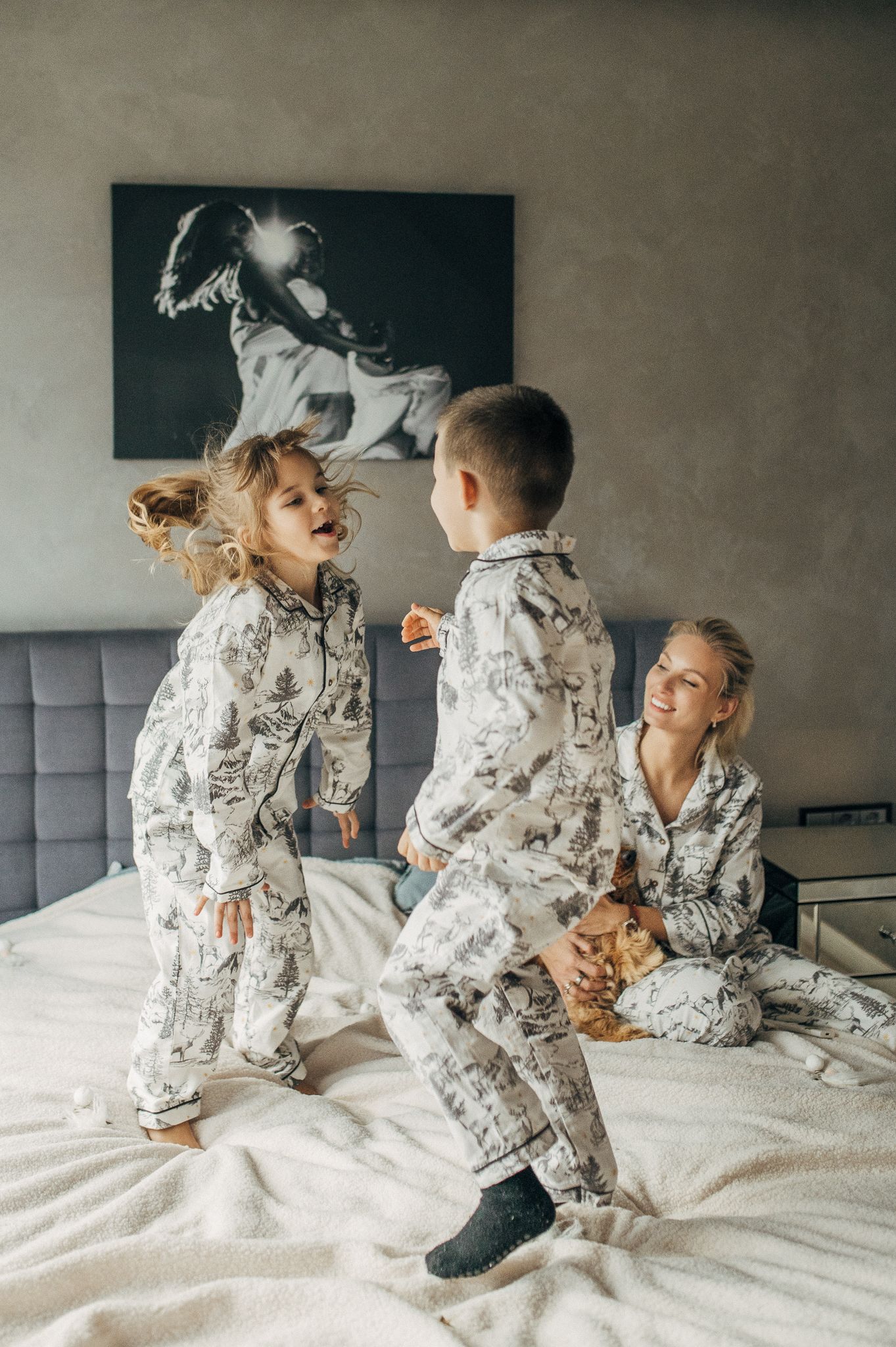 Family wearing matching patterned pajamas playing together on white bedding.