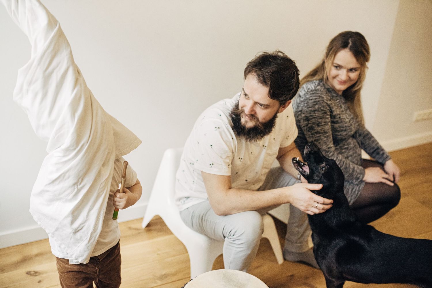Family playing with their black dog in a bright indoor setting.
