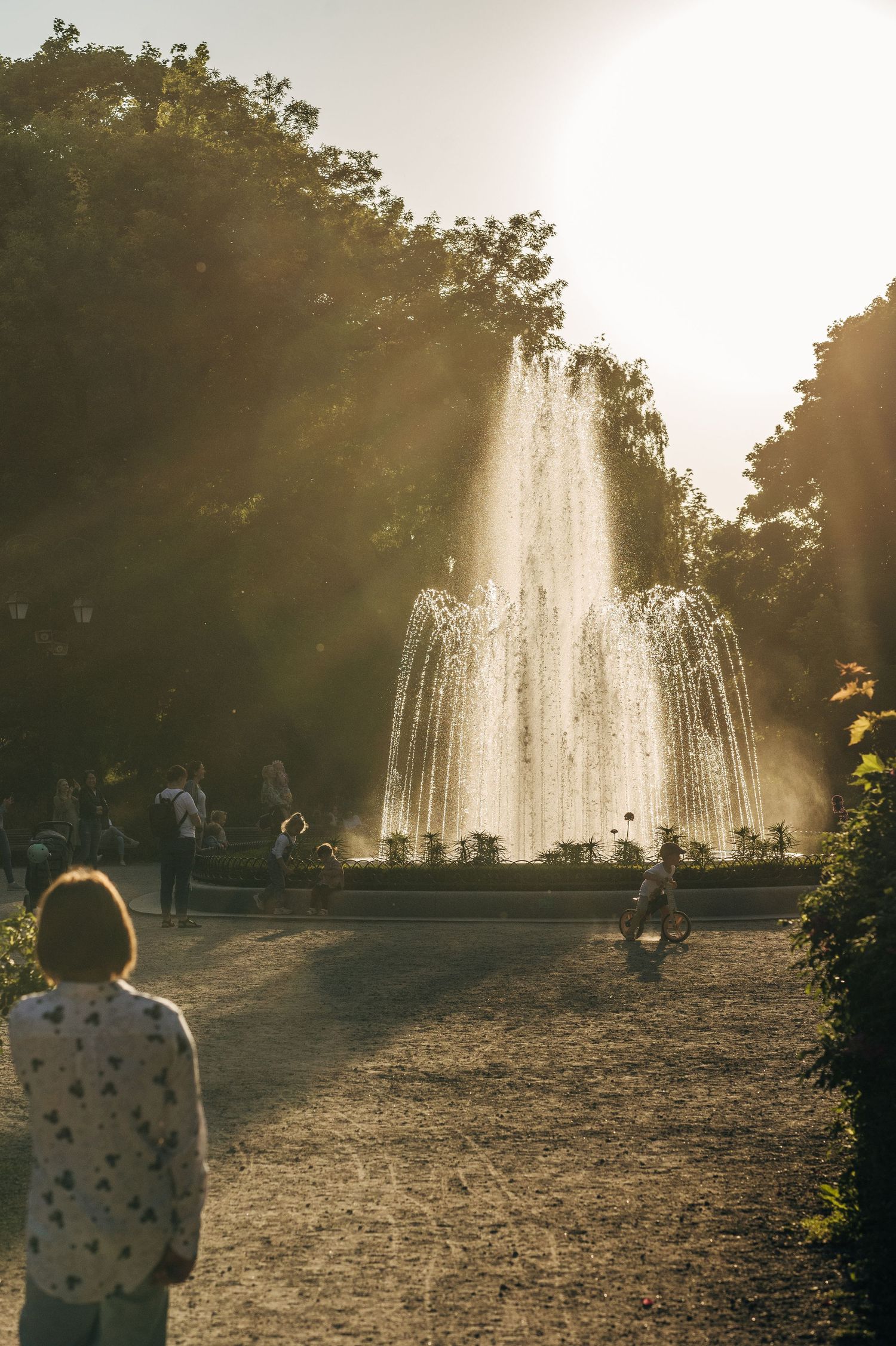 Silhouette against magnificent fountain spray at sunset in a park setting.