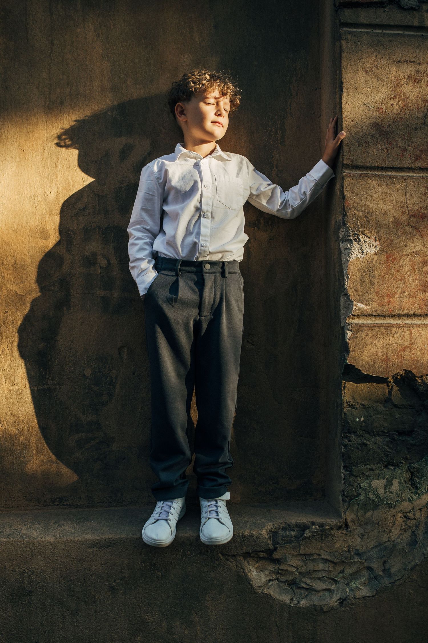 A series of moody portraits showing a small figure against a dark textured wall.