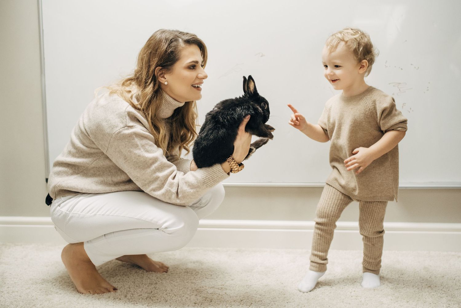 Mother and baby playing together on white floor.