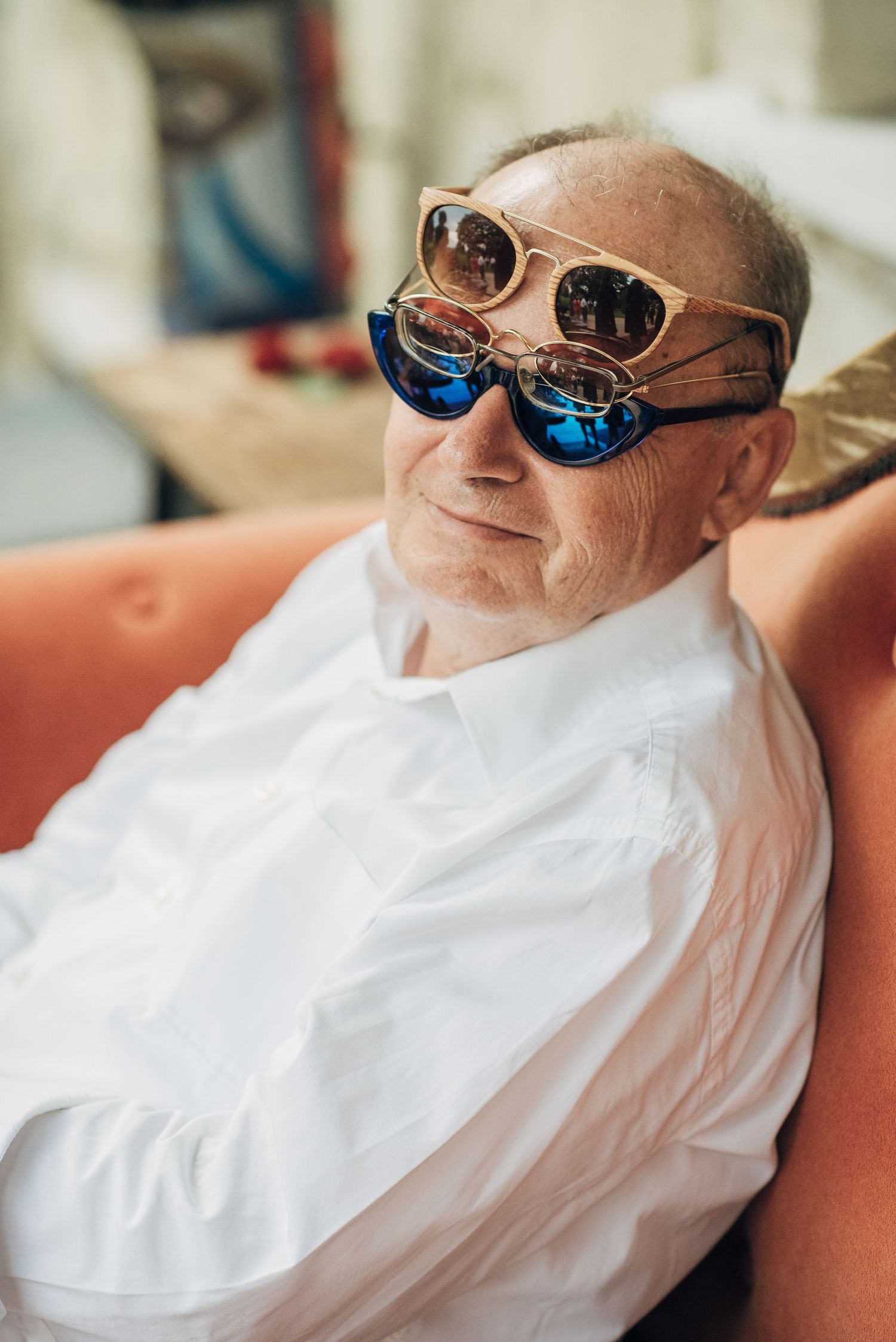 Person relaxing in white attire and reflective sunglasses on a comfortable couch.