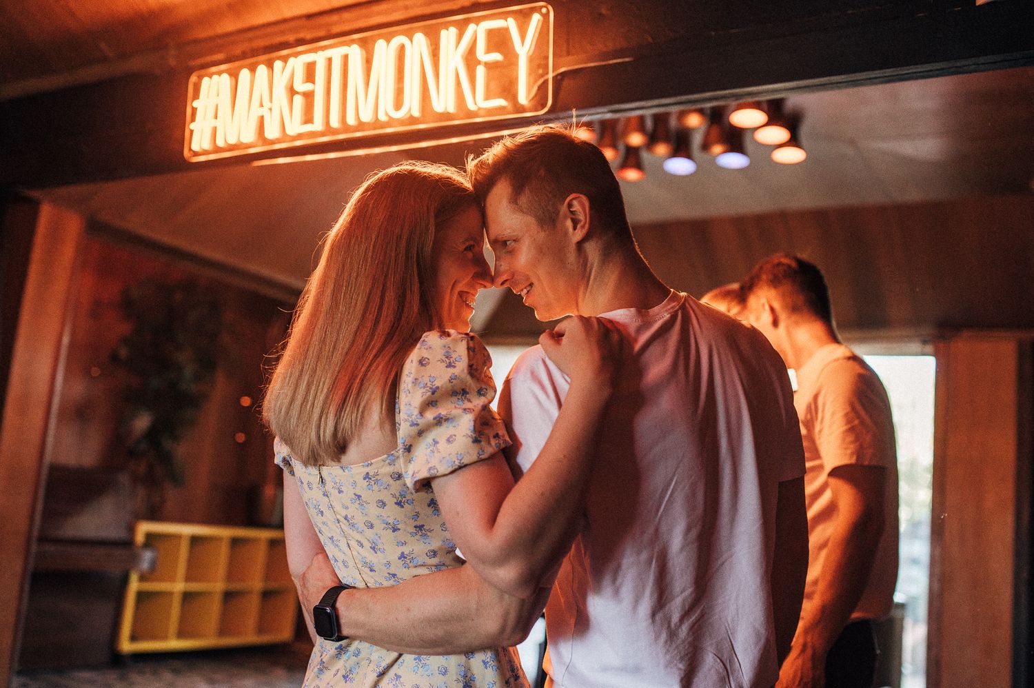 A romantic moment under warm neon lighting in an urban setting.