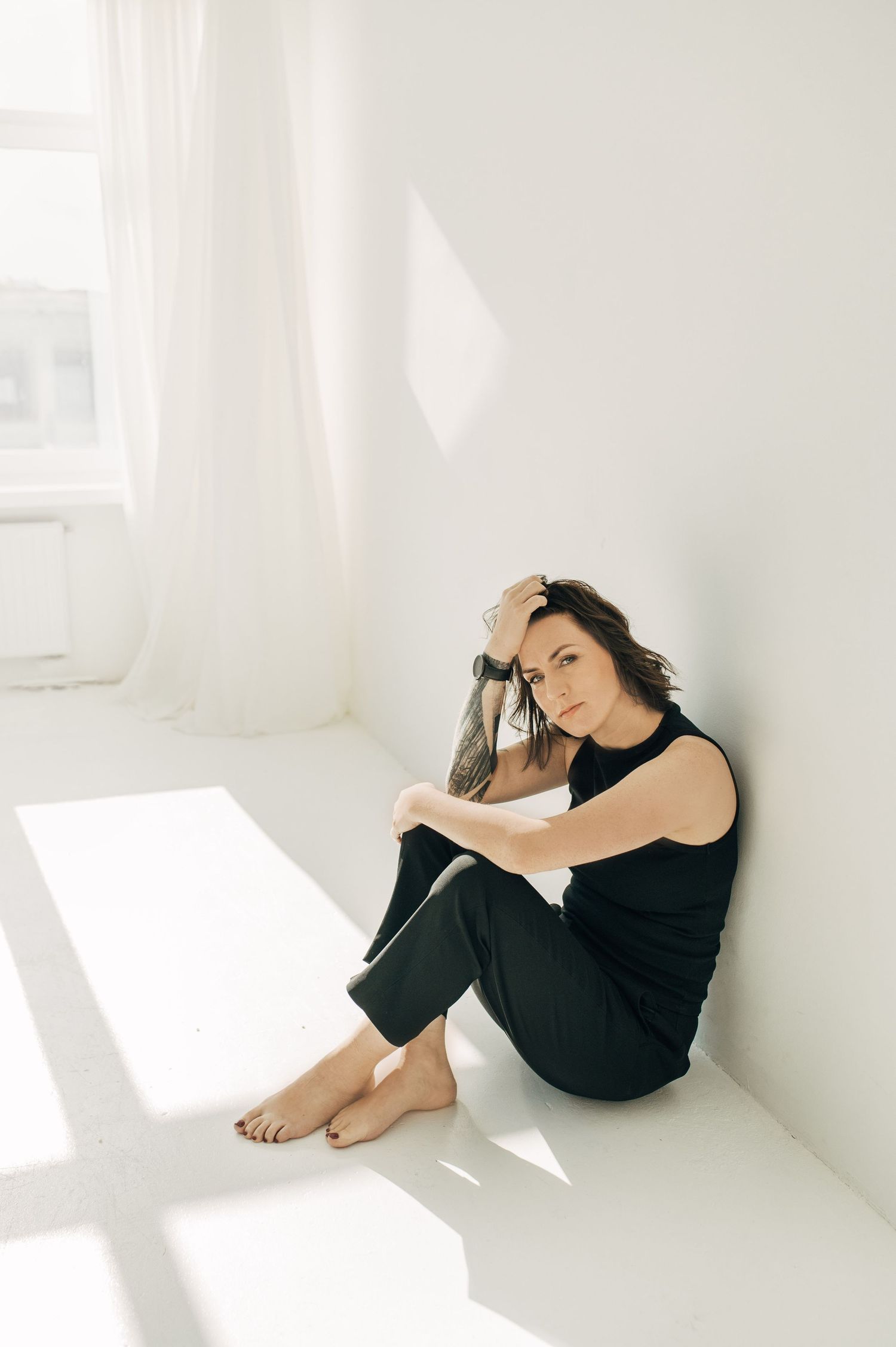 Minimalist white studio portraits showing curled up poses with dramatic shadows.