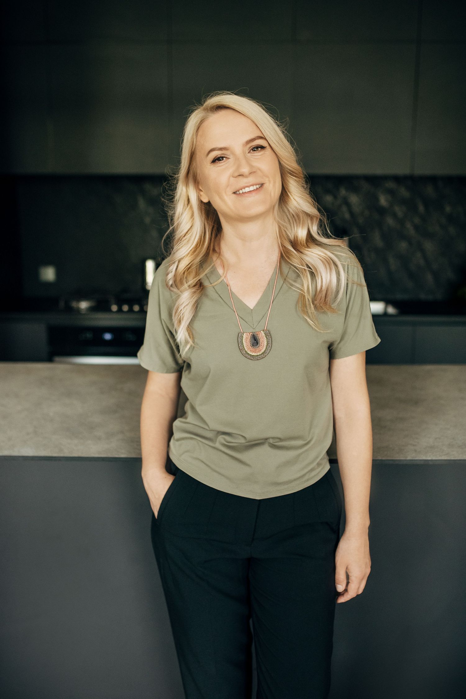 Casual portraits of someone wearing an olive green top and black pants.