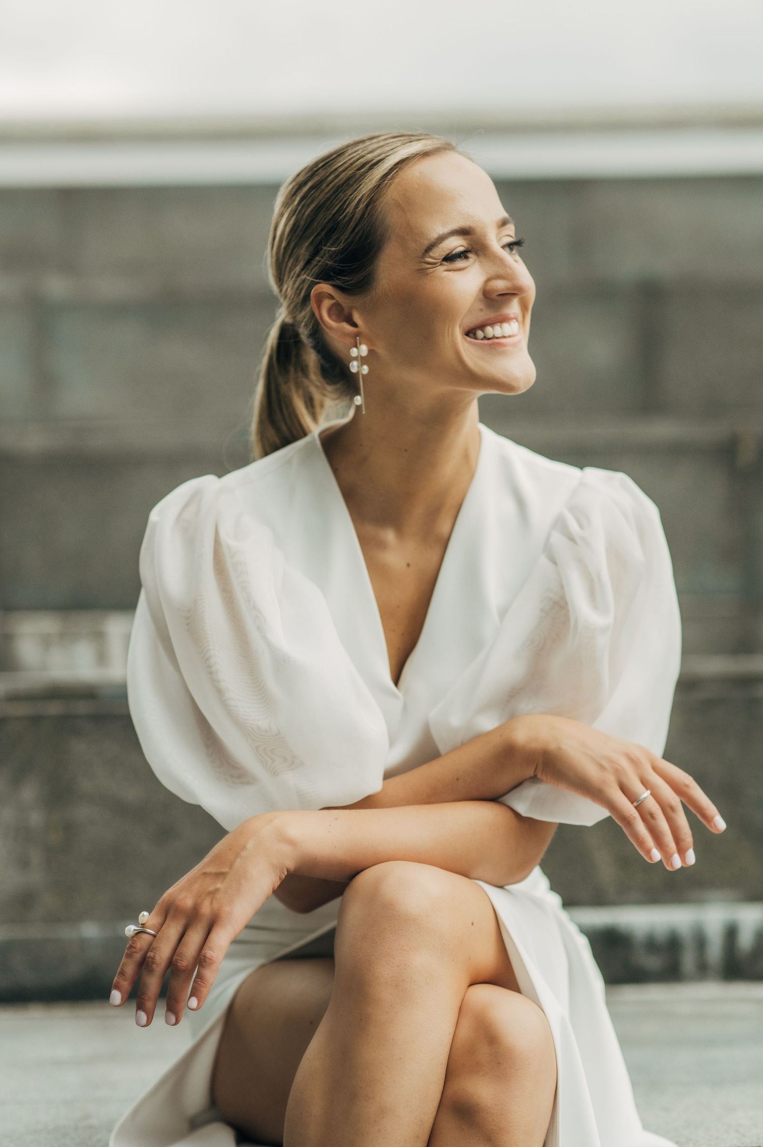 Person in white robe sitting relaxed on grey surface in natural light.