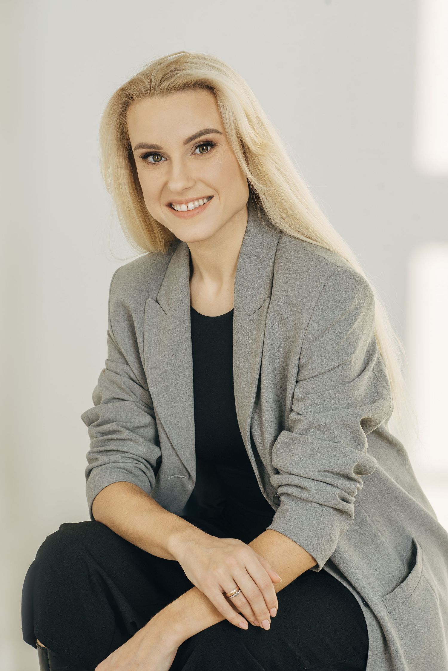 Modern business portrait in grey blazer and black top against bright studio setting.