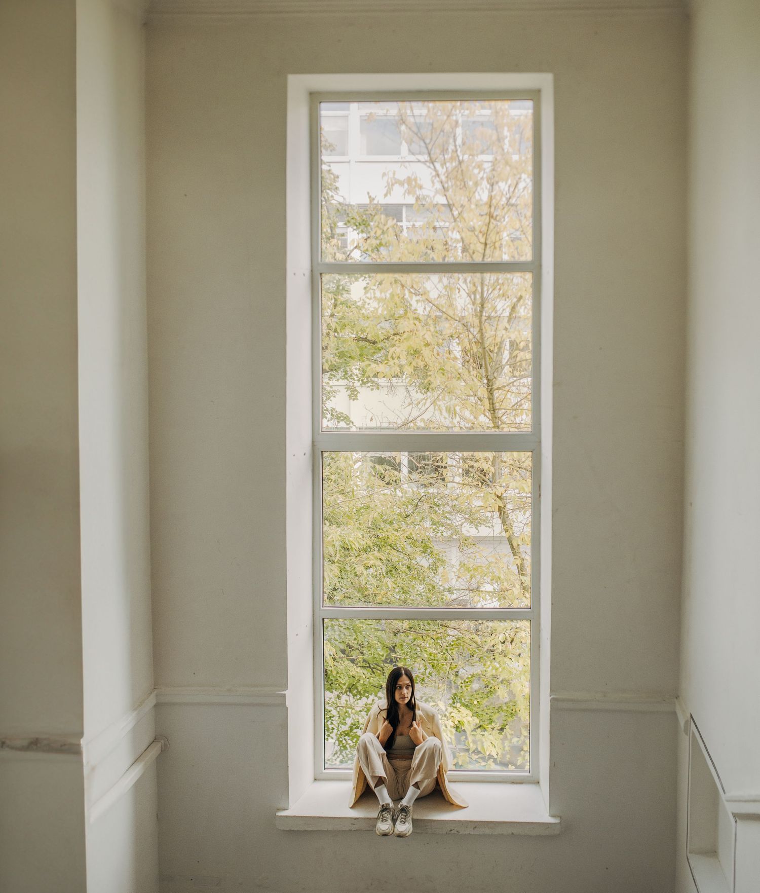 Bright minimalist room with large windows showing multiple poses on windowsill.