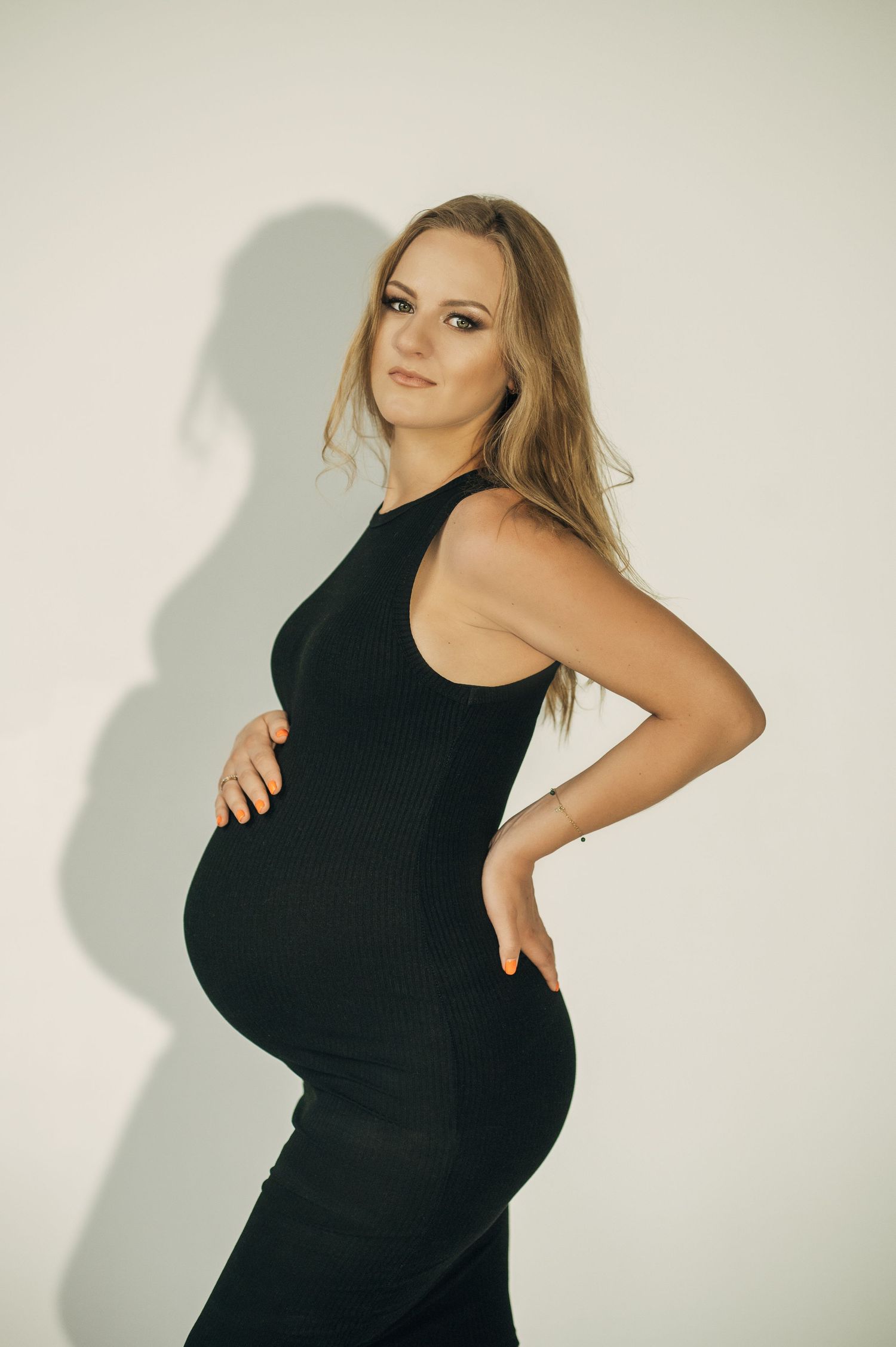 Series showing a pregnant woman in a black dress posing against a light background.