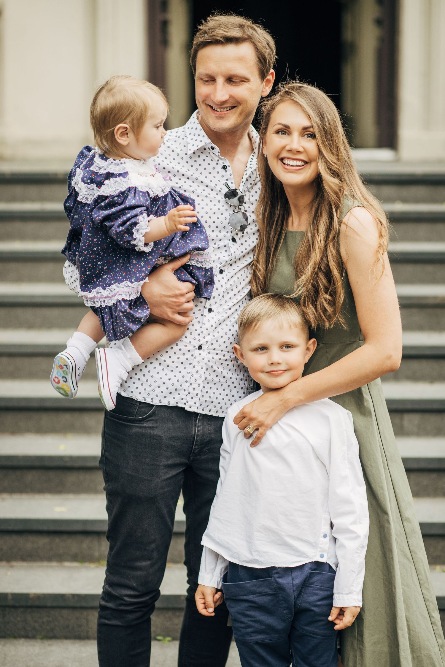Family shares warm embrace on stone steps during casual outdoor portrait session.