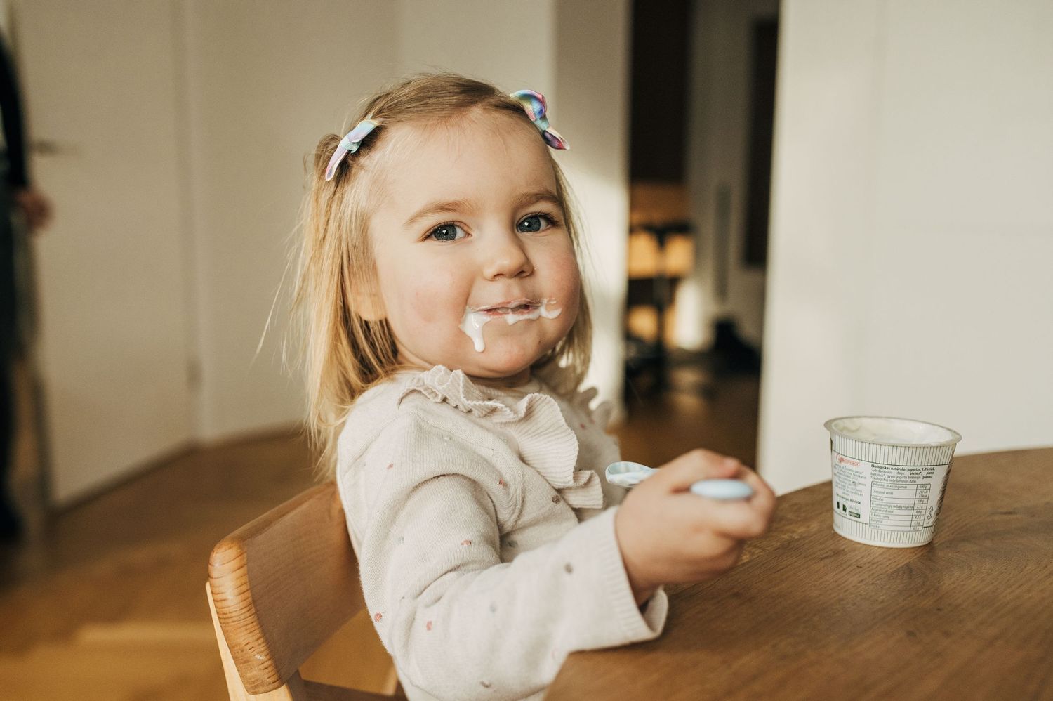 Candid moment at wooden table with glass and gentle natural lighting.