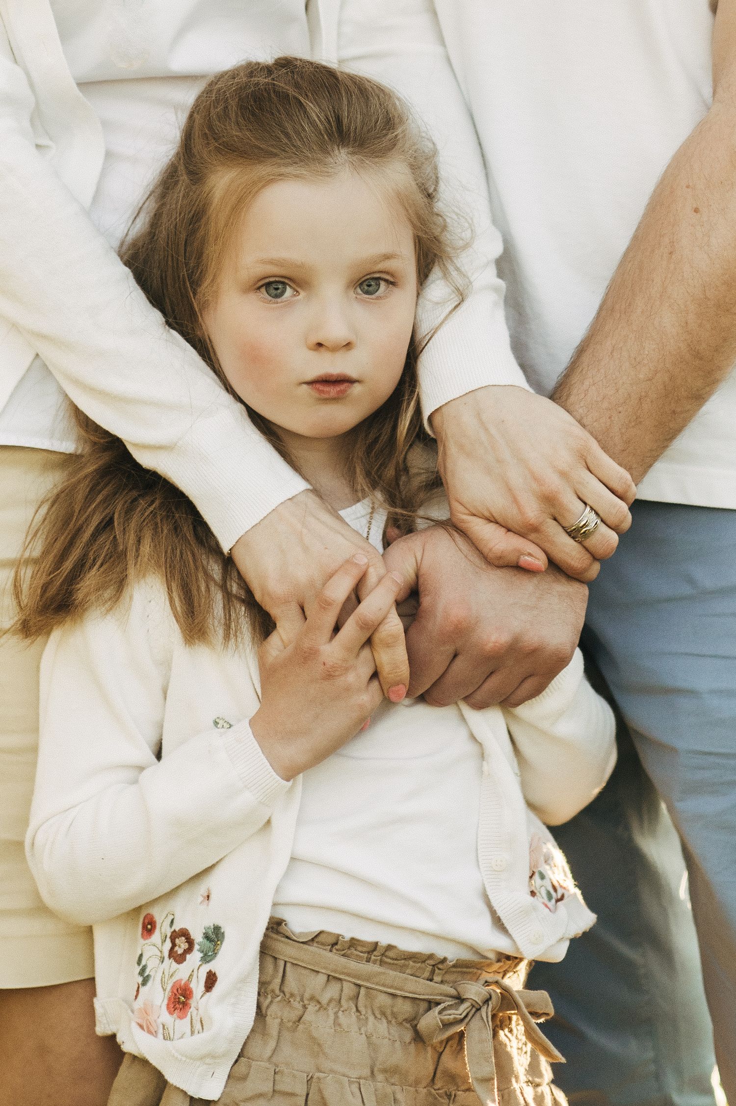 Close-up details of cream-colored clothing and gentle hand holding moments.