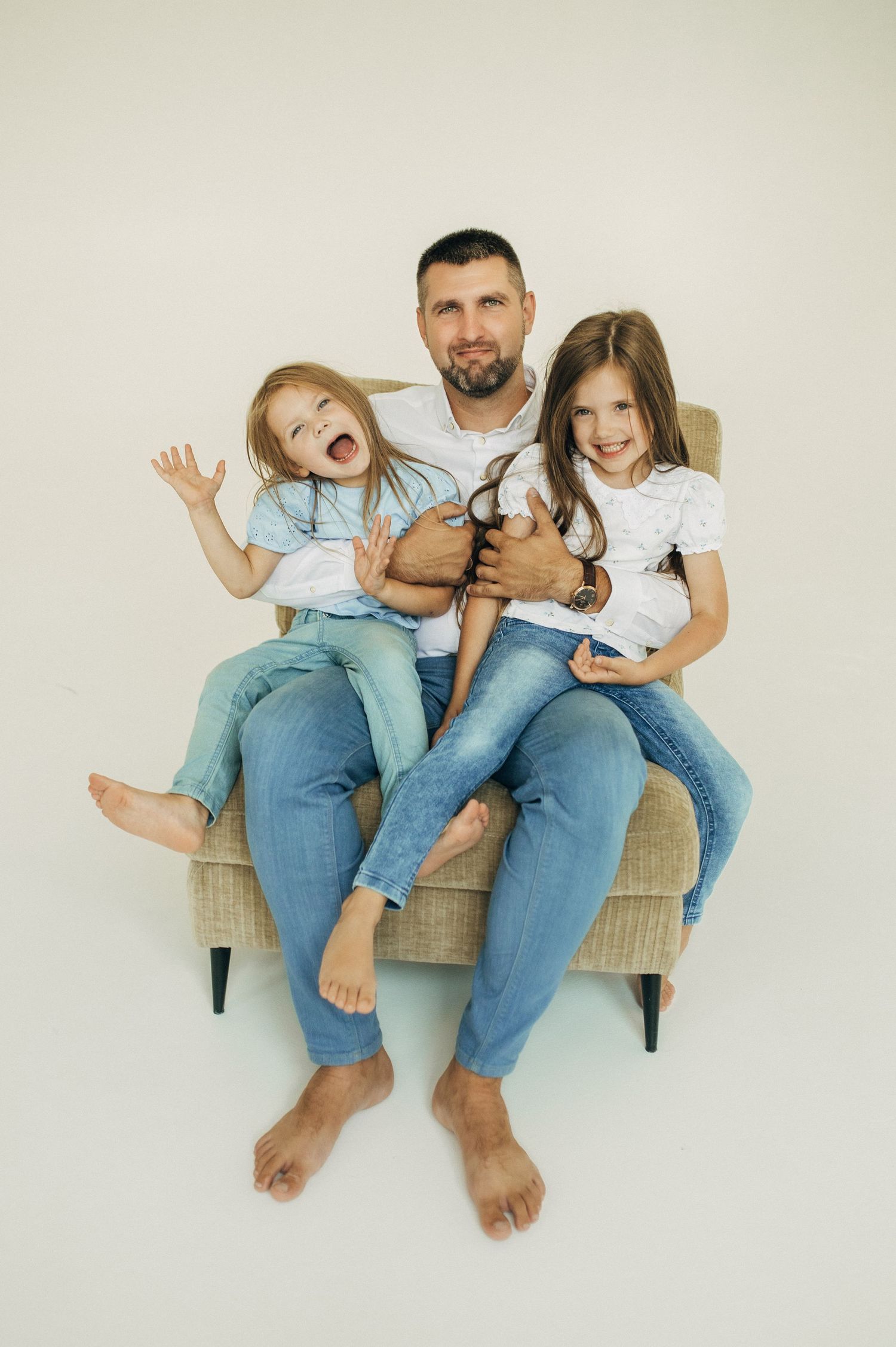 Family relaxing together on woven bench during casual studio photoshoot.