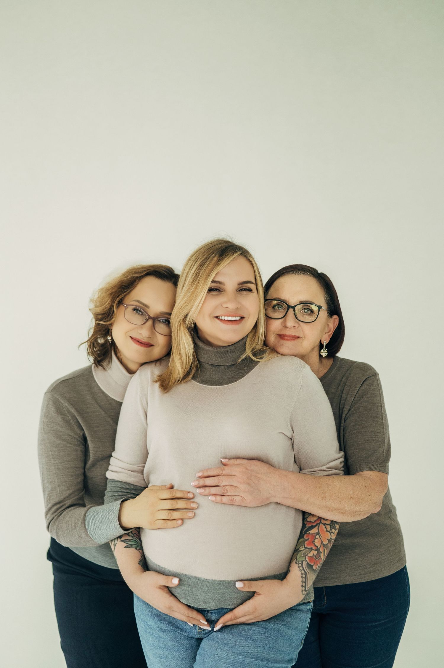 A group hugs and shows affection for a pregnant woman in a light colored top.