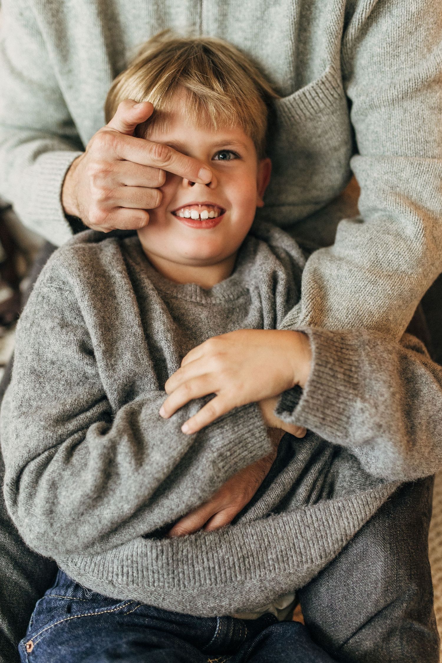 Close up shots of a playful child in a gray sweater showing joyful expressions and gestures.