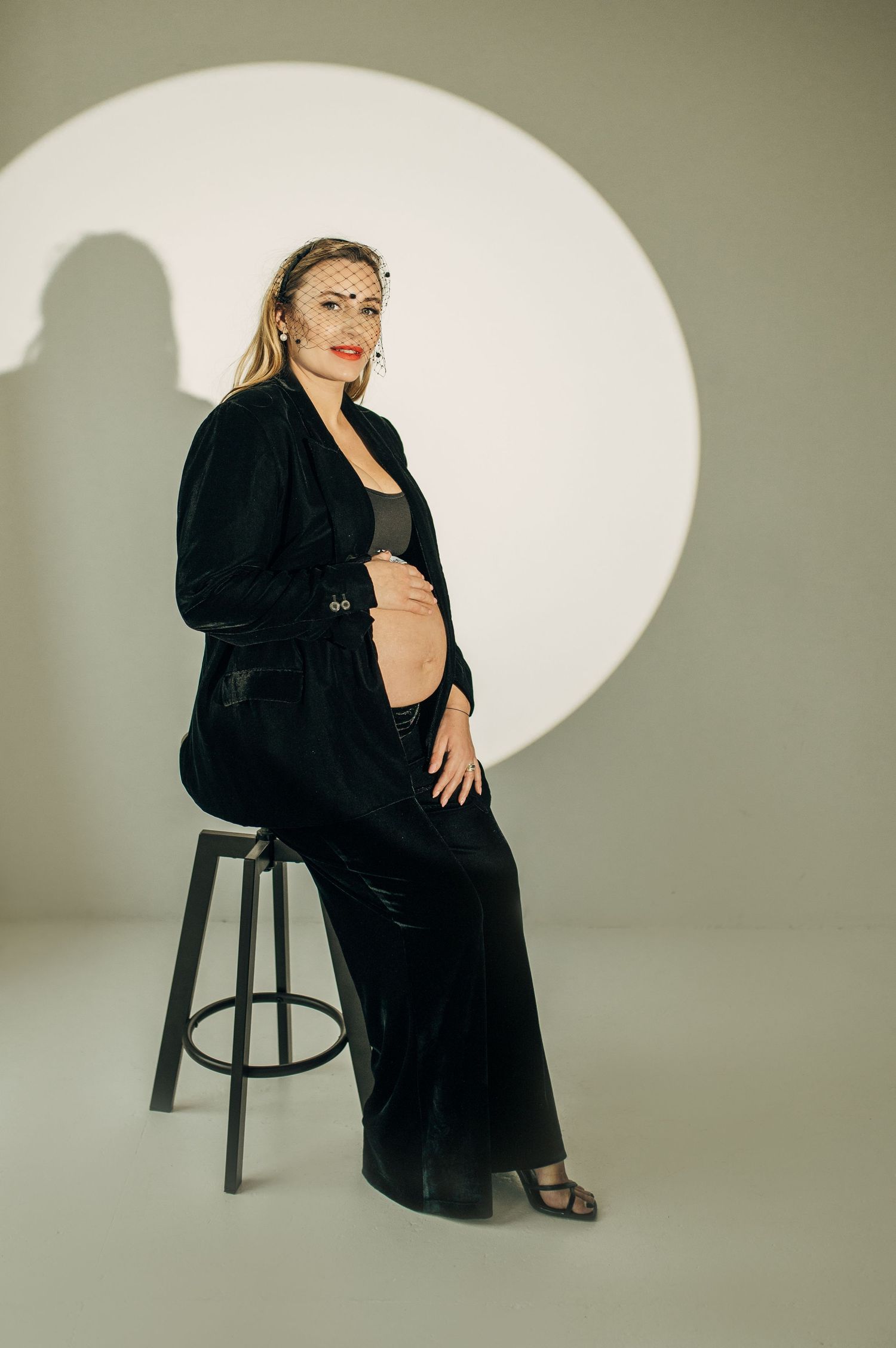Dramatic studio portraits against a light backdrop with a circular spotlight and black clothing.