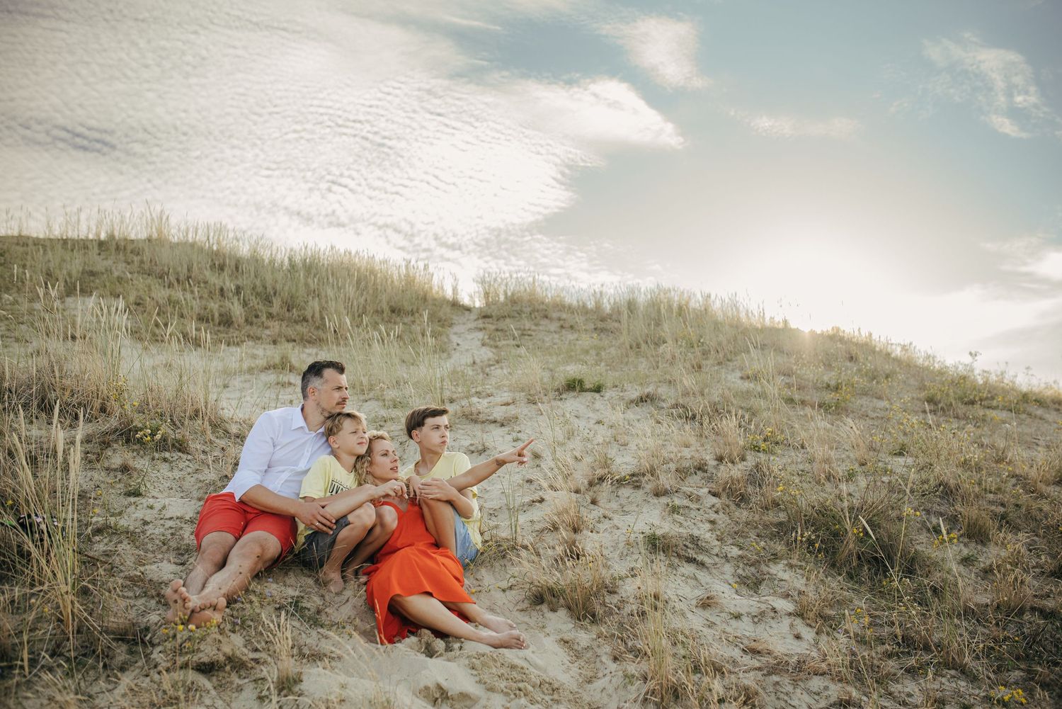 Family enjoying a sunny day together on a grassy hillside.