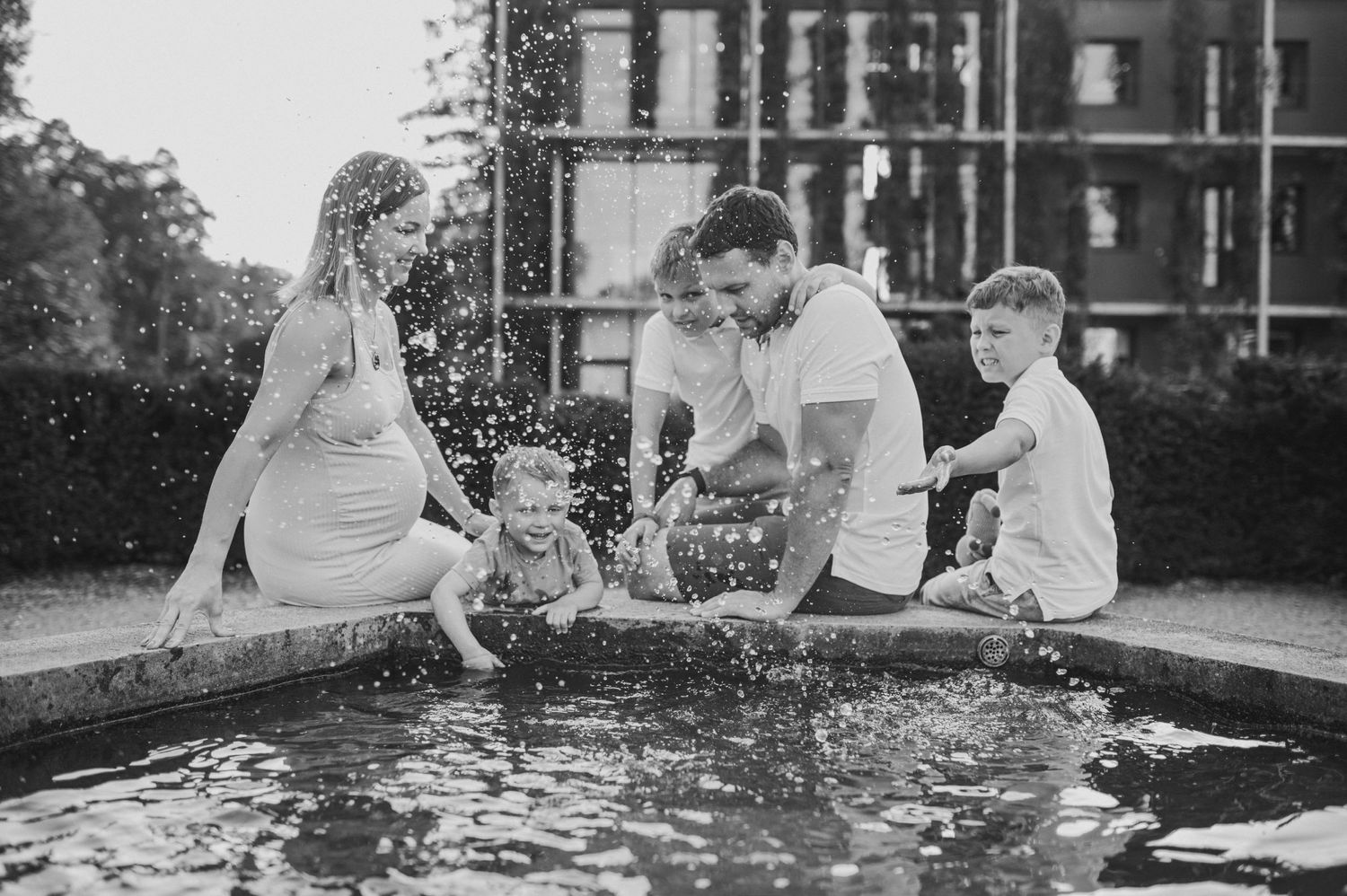 Children playing and splashing in water during an outdoor family photoshoot.