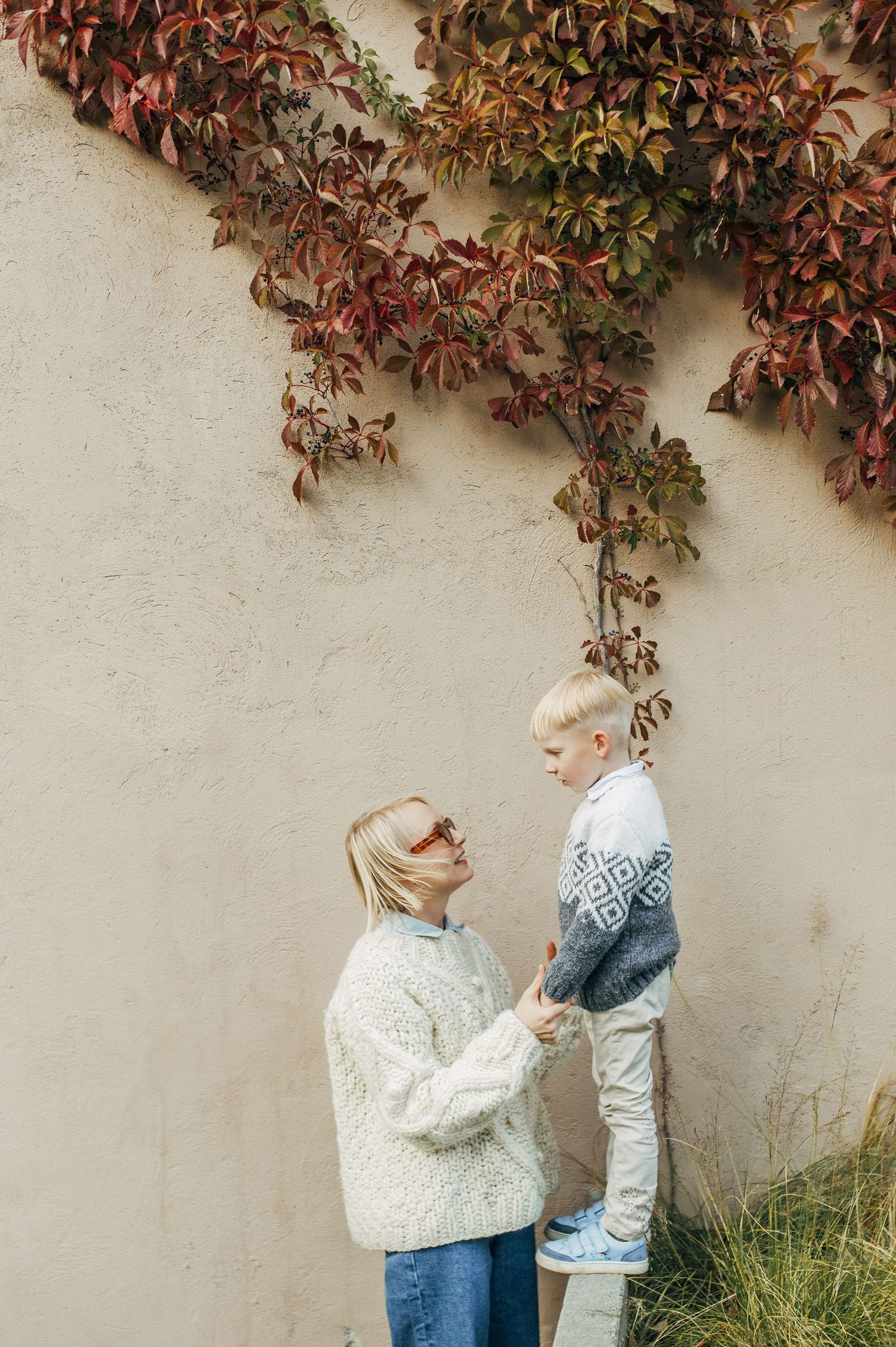 Series of photos capturing tender parent-child moments against a wall with autumn vines.