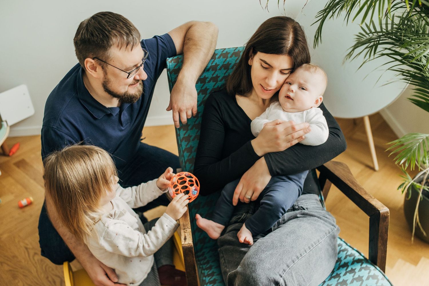 Casual family moment on floor with toys and natural light from window.