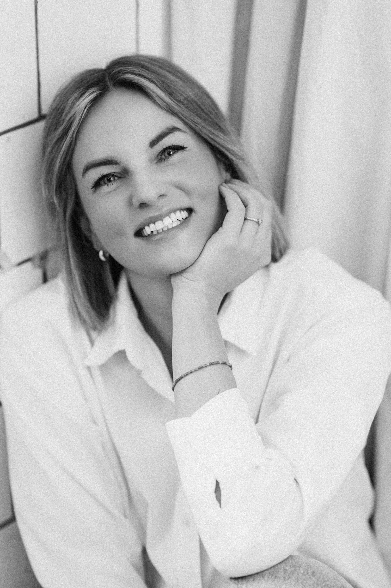 Black and white portrait of person in white shirt with radiant smile.