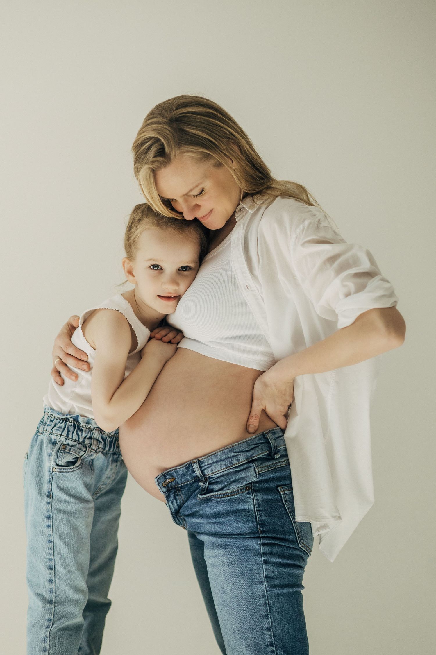 Series showing tender moments between parent and child in minimal studio setting with white walls.