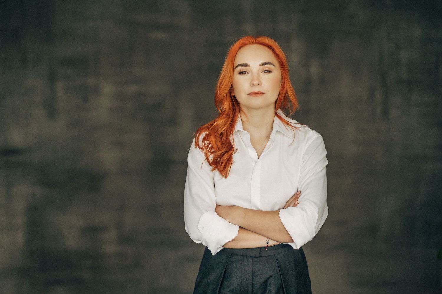 Professional portrait with someone in white business attire against dark textured background.