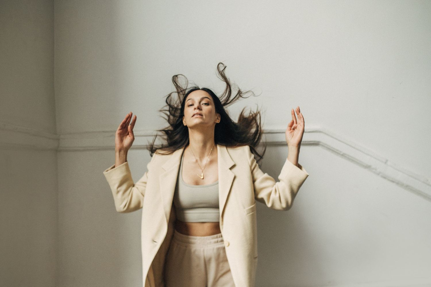 Dynamic movement sequence of person in cream colored suit against light backdrop.