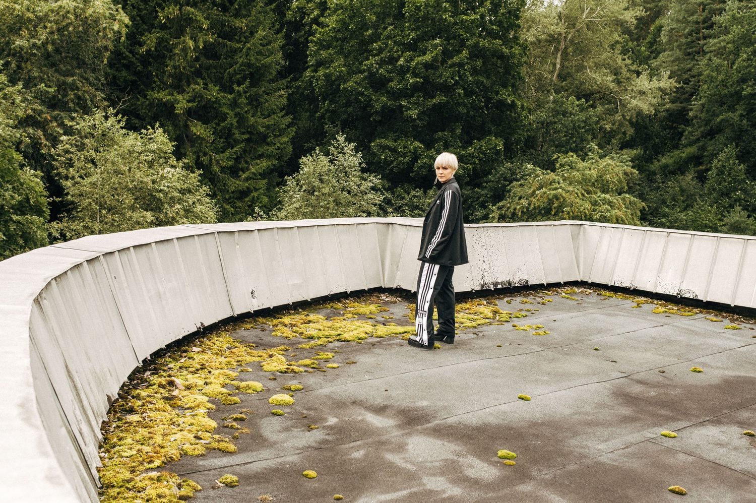 Outdoor fashion series on a curved concrete path with fallen autumn leaves.
