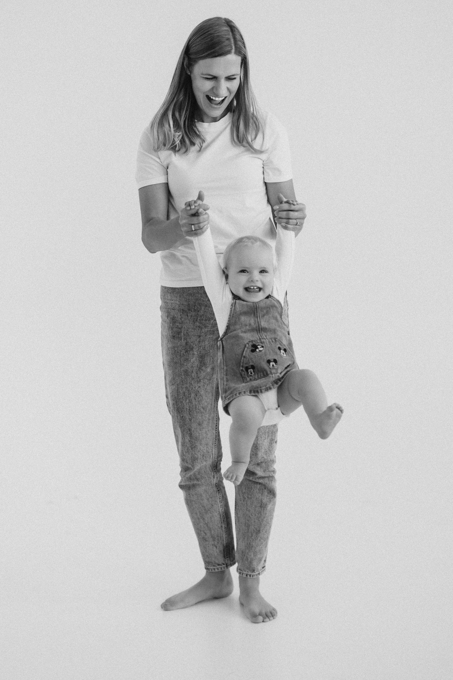 A series of three black and white photos showing a small child playing and standing while wearing casual clothing.