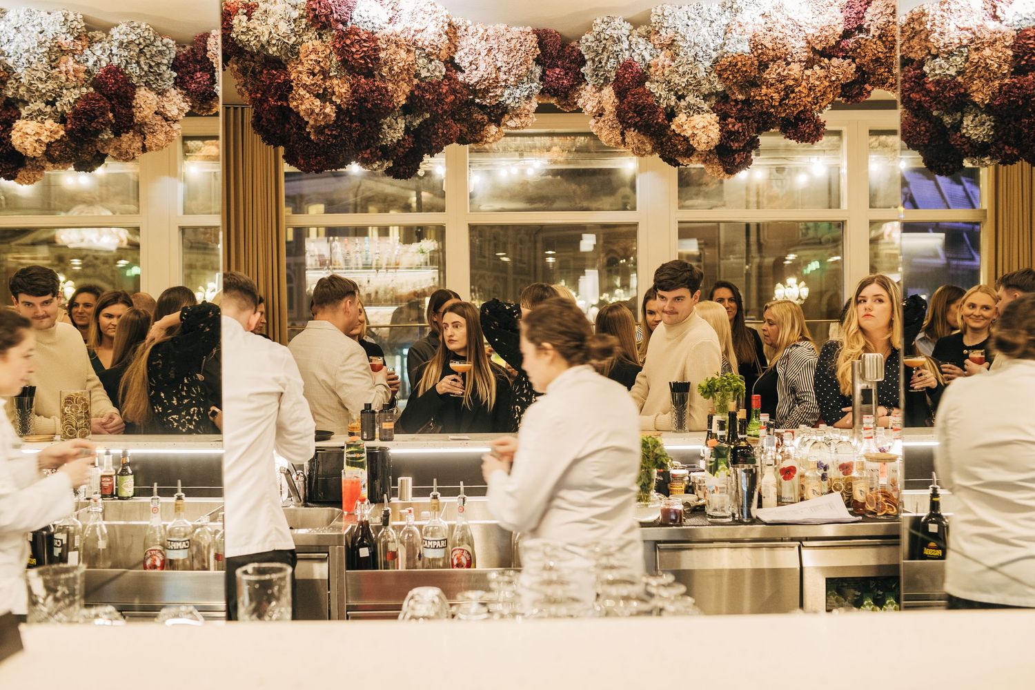 A wedding reception venue decorated with pink floral arrangements and illuminated by warm lighting.