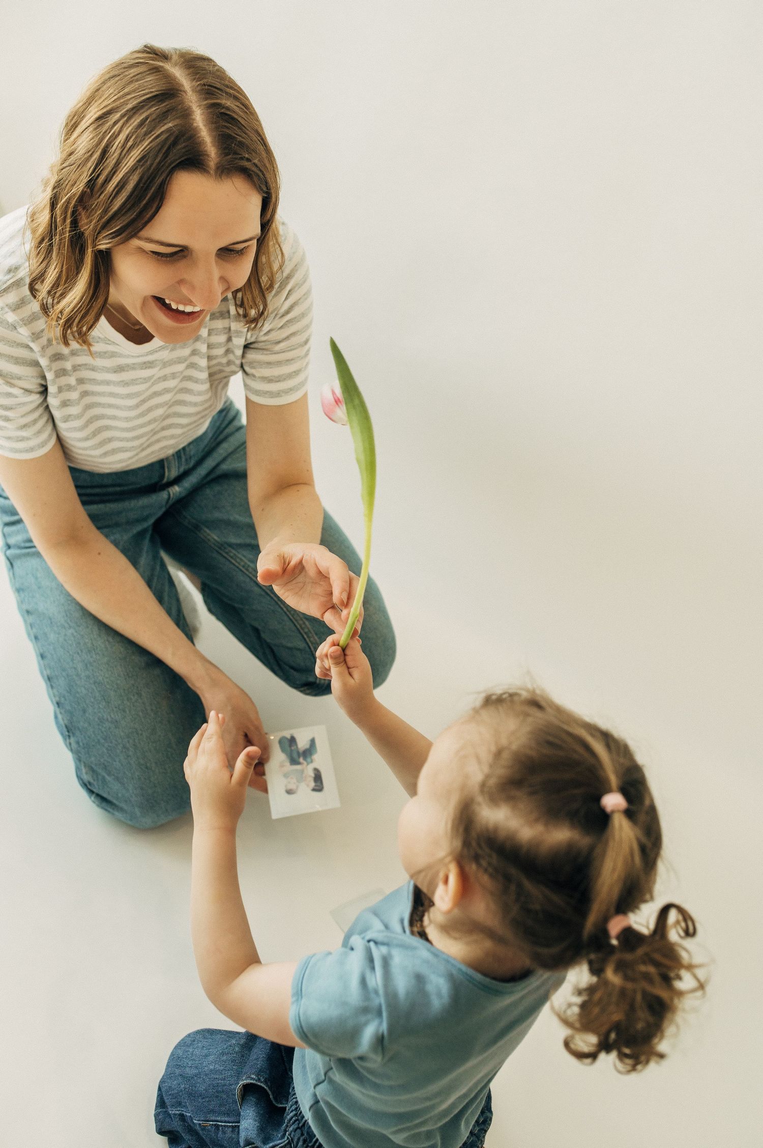 Parent and child playing together on floor in casual denim outfits.