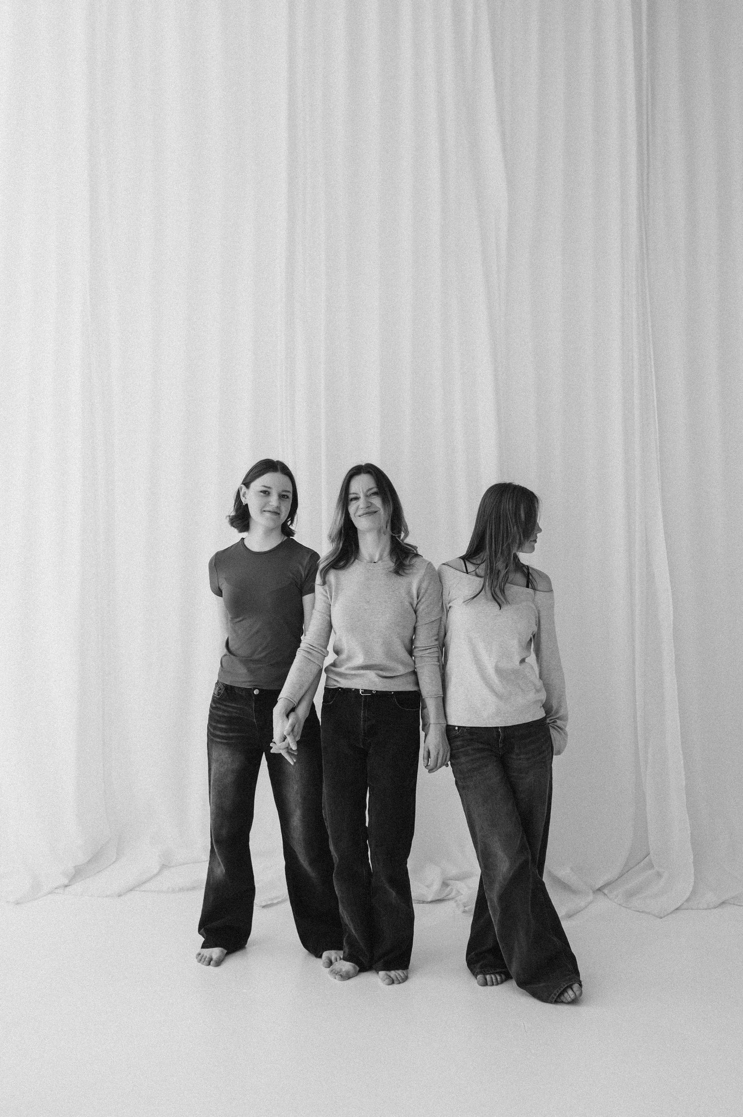 Black and white portrait of people sitting together against a white curtain background.