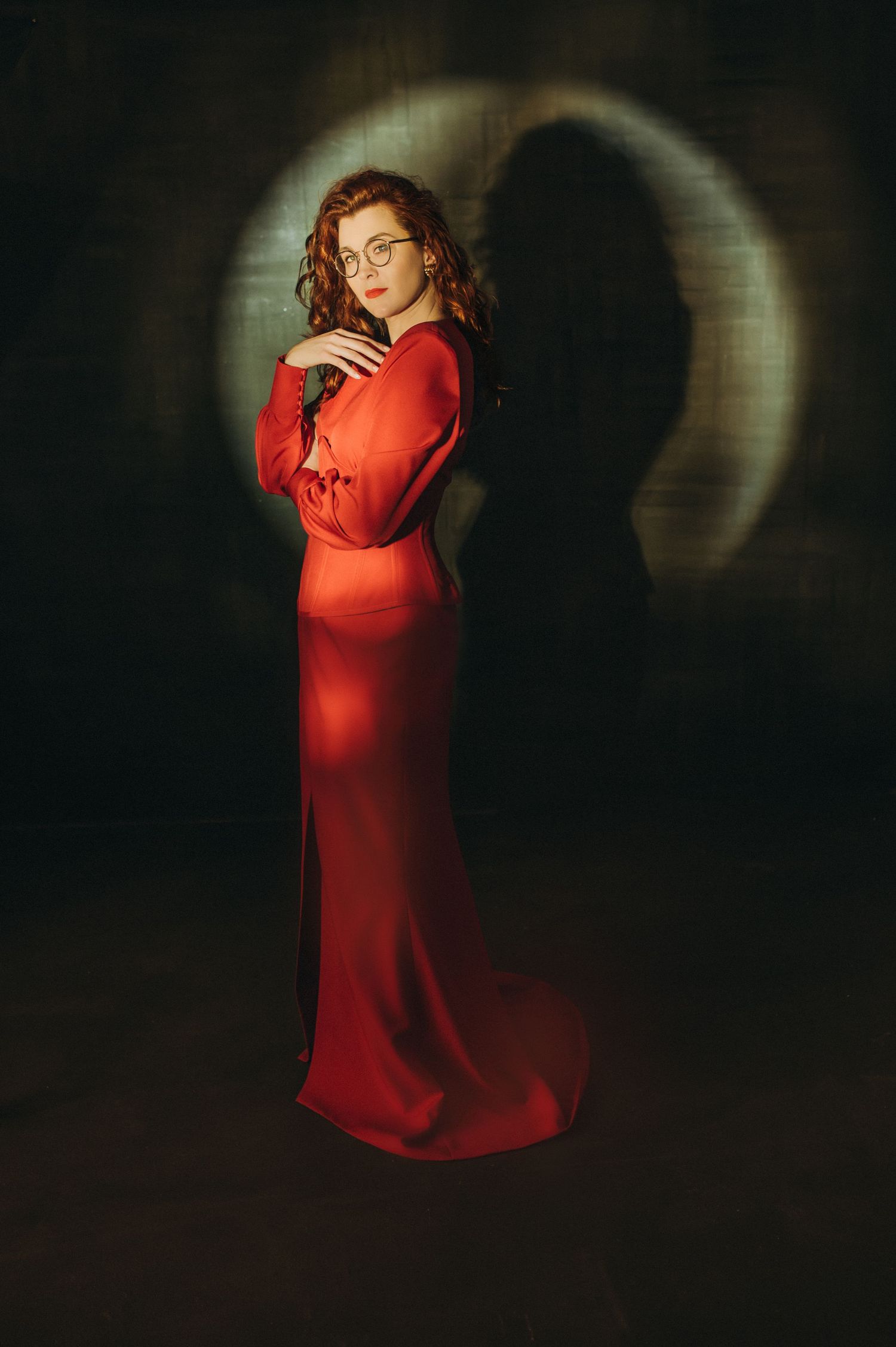 Figure in a flowing red dress creates dramatic silhouettes against a dark background in artistic photo series.