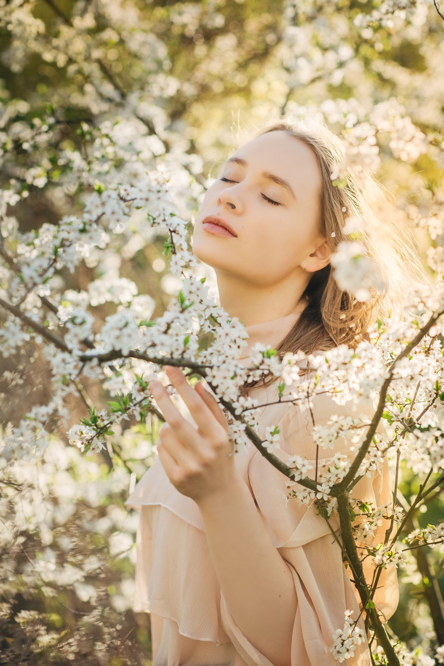 Romantic portrait amidst blooming cherry blossoms with soft natural lighting creating an ethereal spring mood.