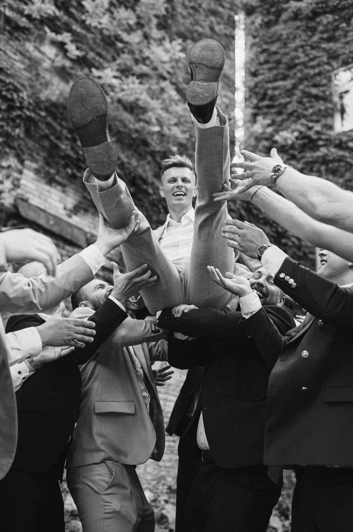 Group photo showing wedding guests doing synchronized dance moves in black and white.