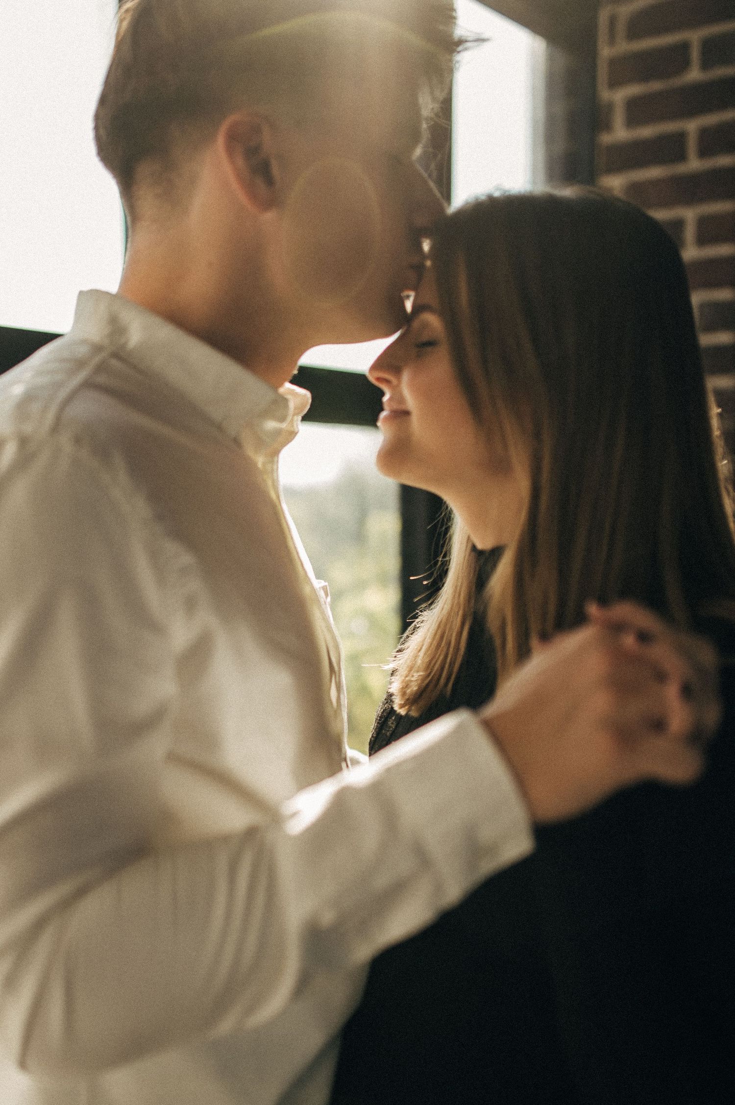 Intimate backlit couple portraits near windows with romantic lighting effects.