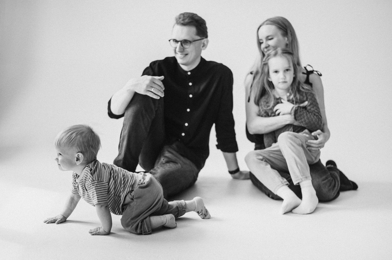 Black and white family portrait session showing candid moments on white backdrop.