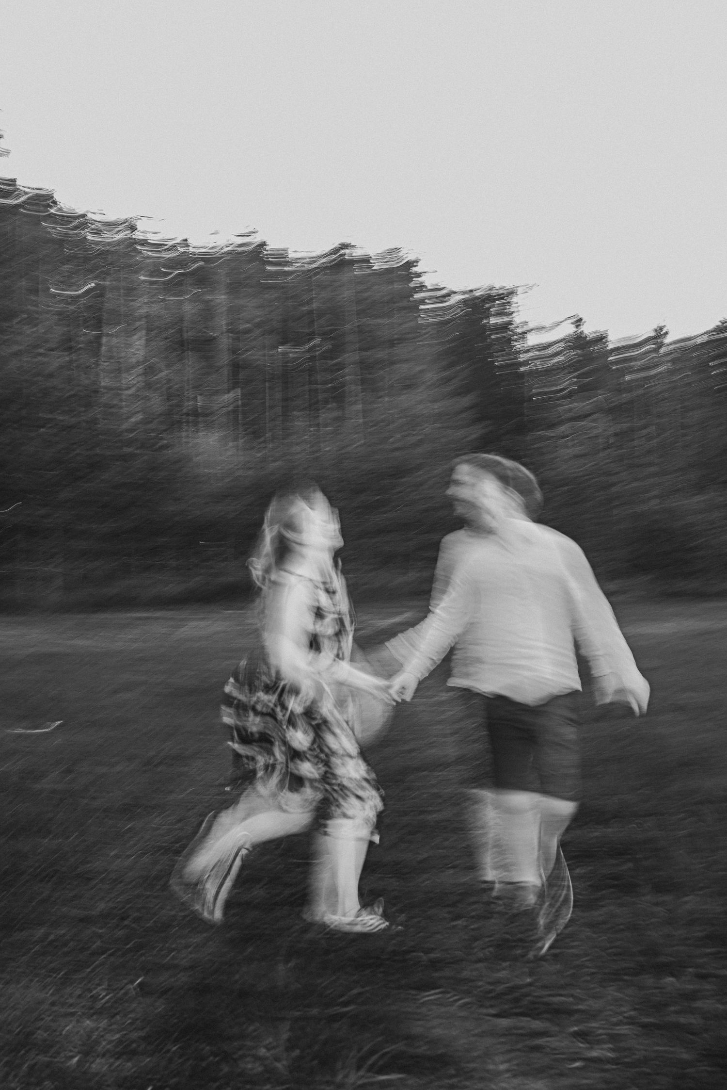 Black and white motion blur photo of figures dancing in a field.