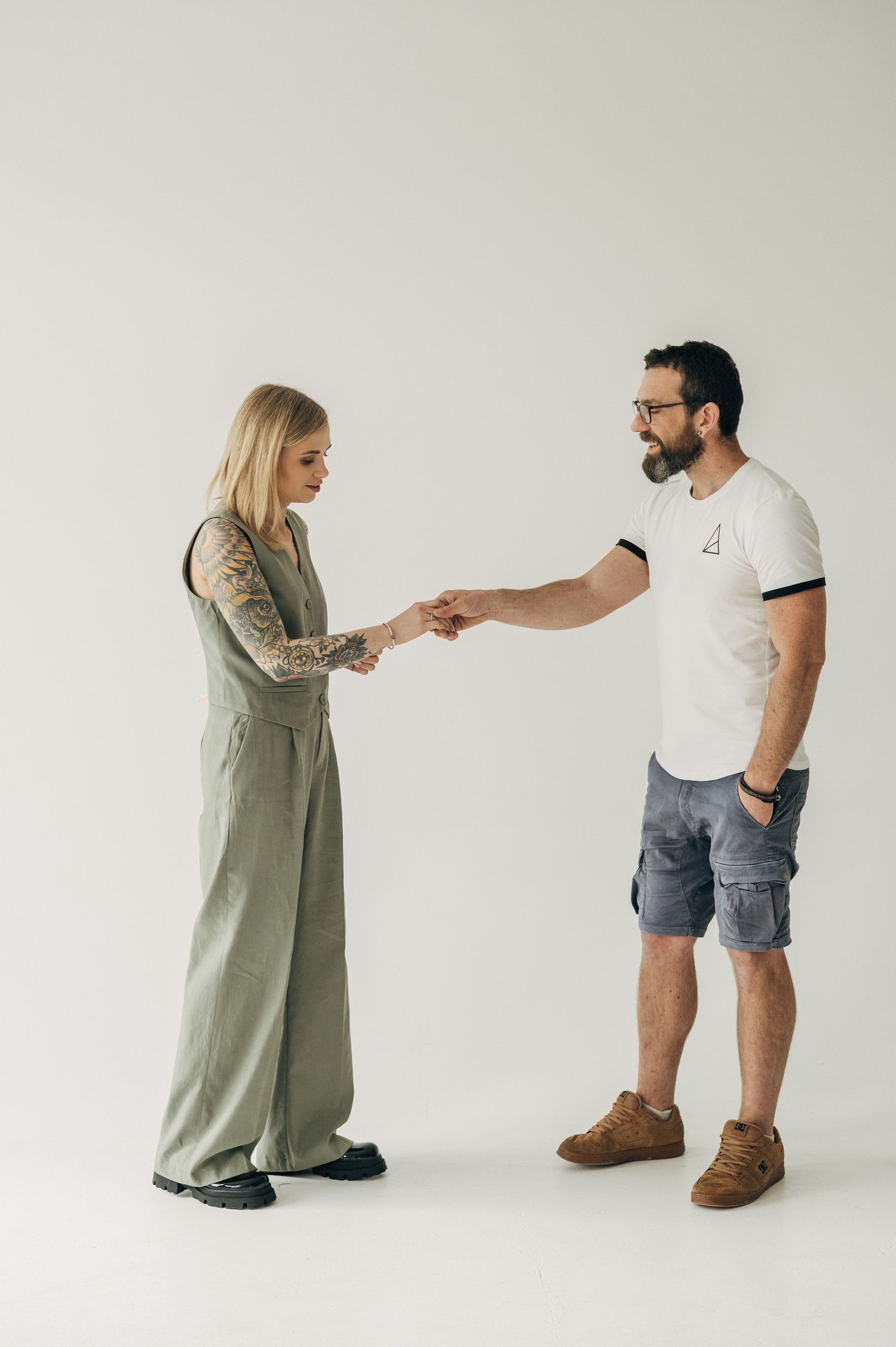Two people shake hands while standing against white background.