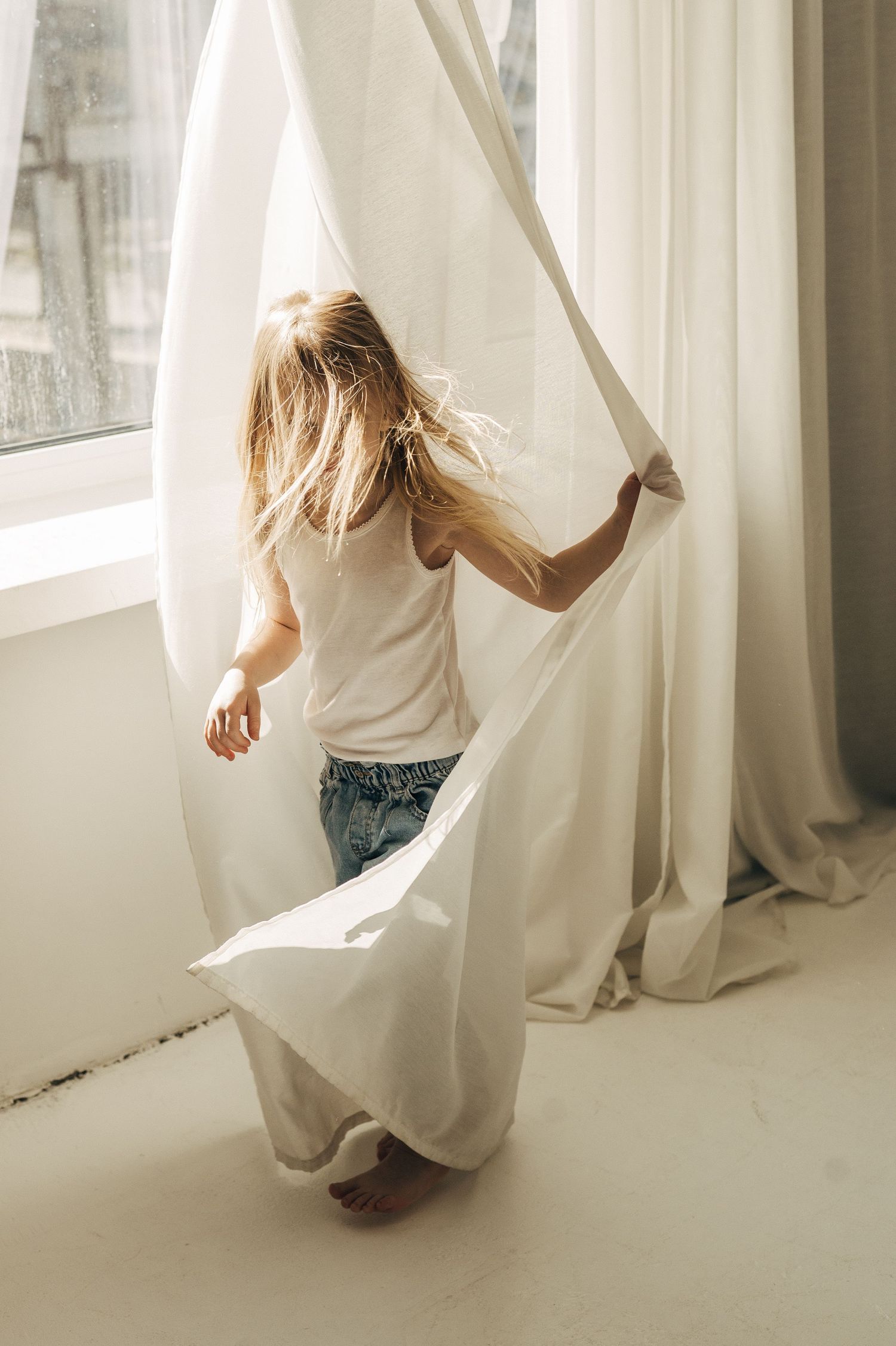 Ethereal sequence of someone dancing with flowing white curtains in a sunlit room.