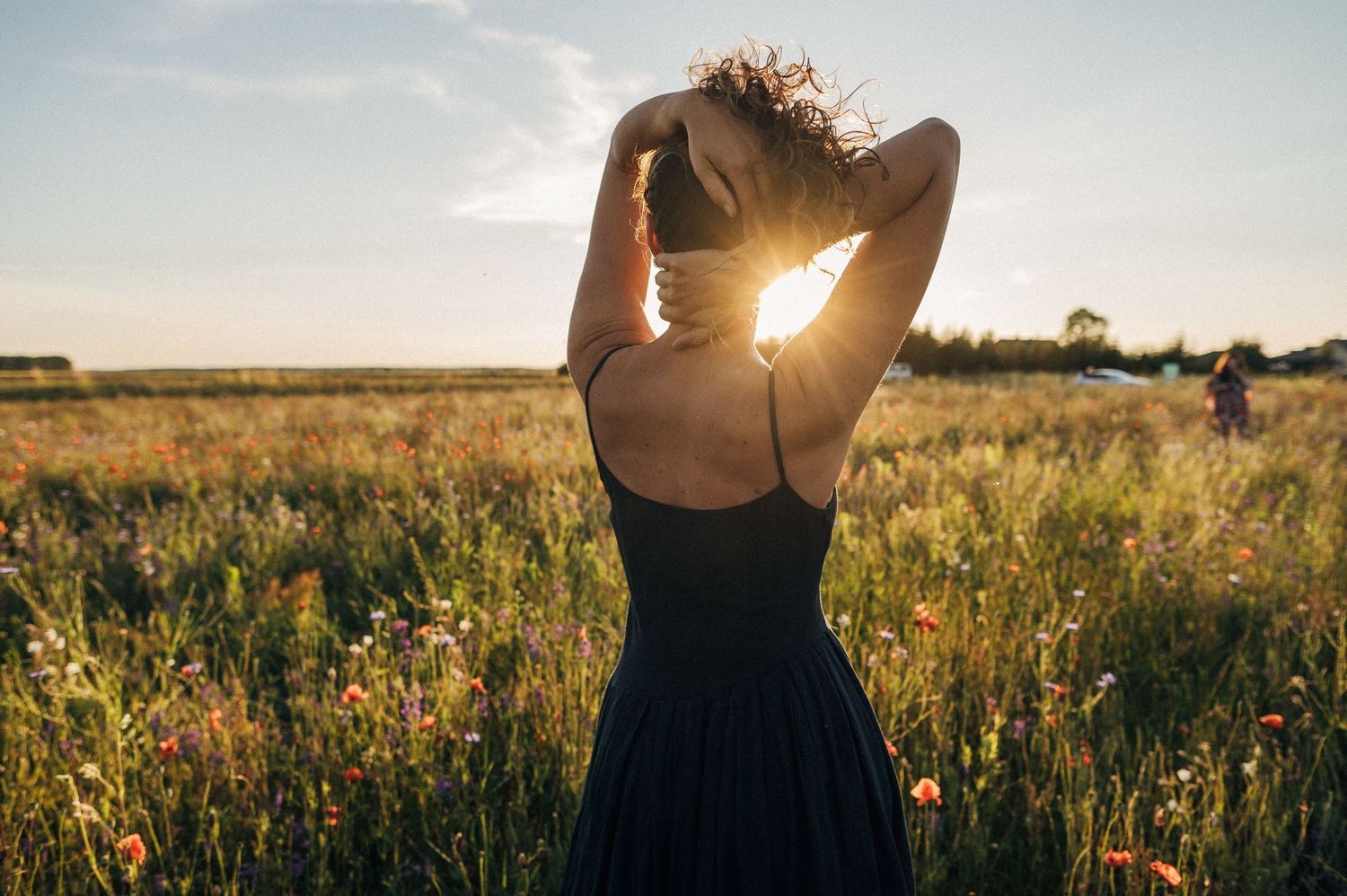 Golden sunlight streams through a summer meadow as someone dances among wildflowers.