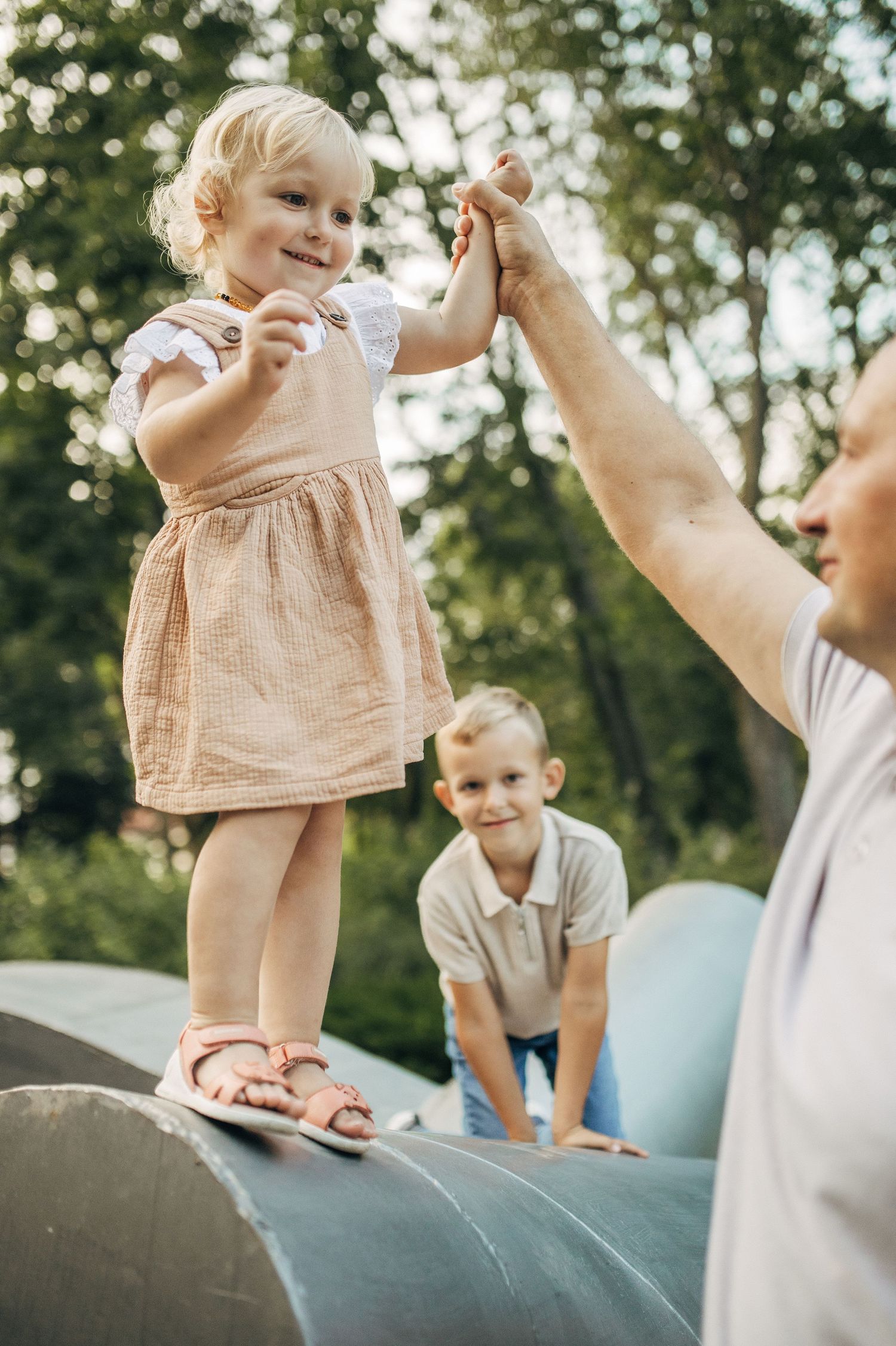 Family playtime sequence on a curved outdoor structure in a sunny park setting.