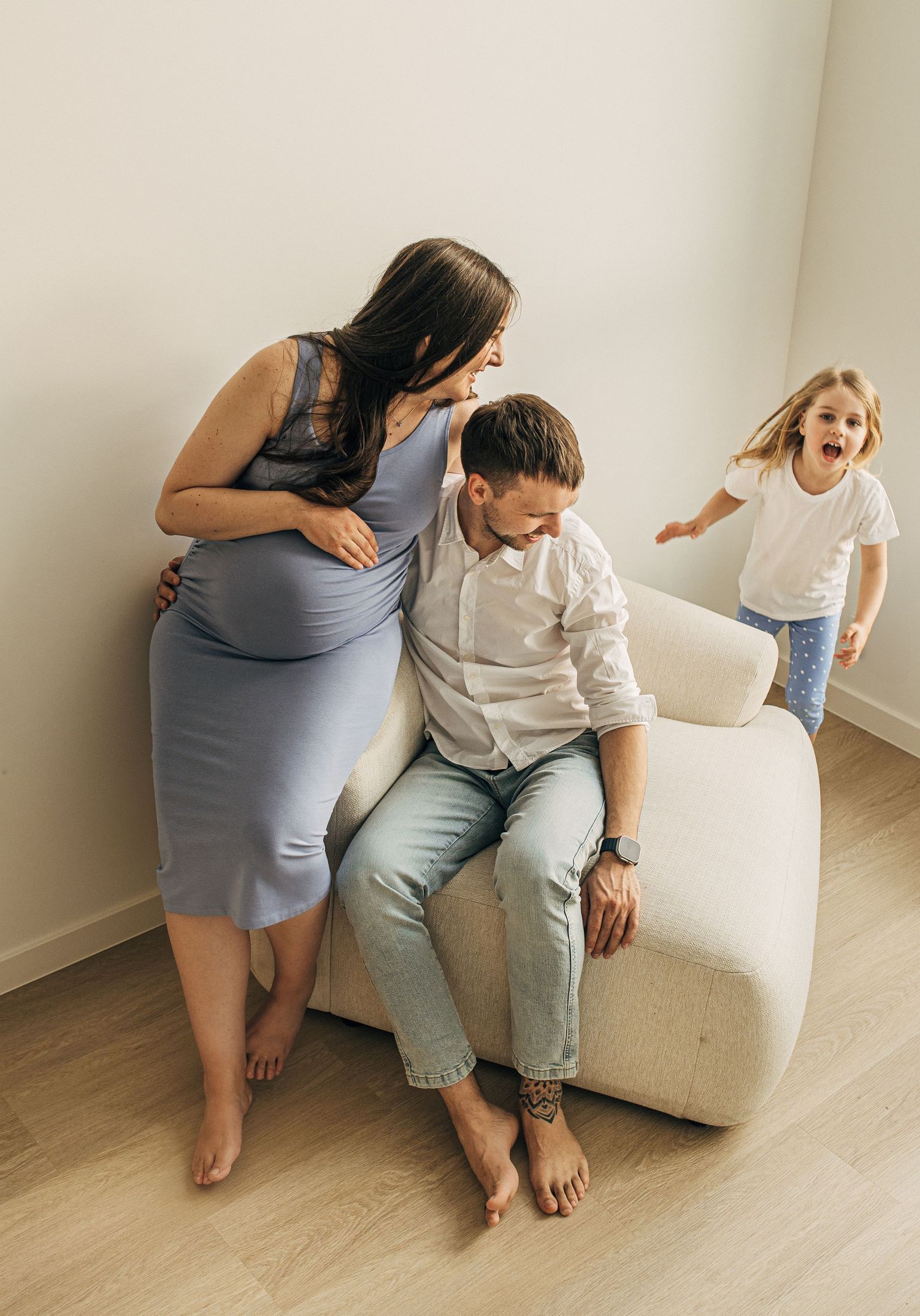 Intimate family moments captured on a white couch with natural lighting.