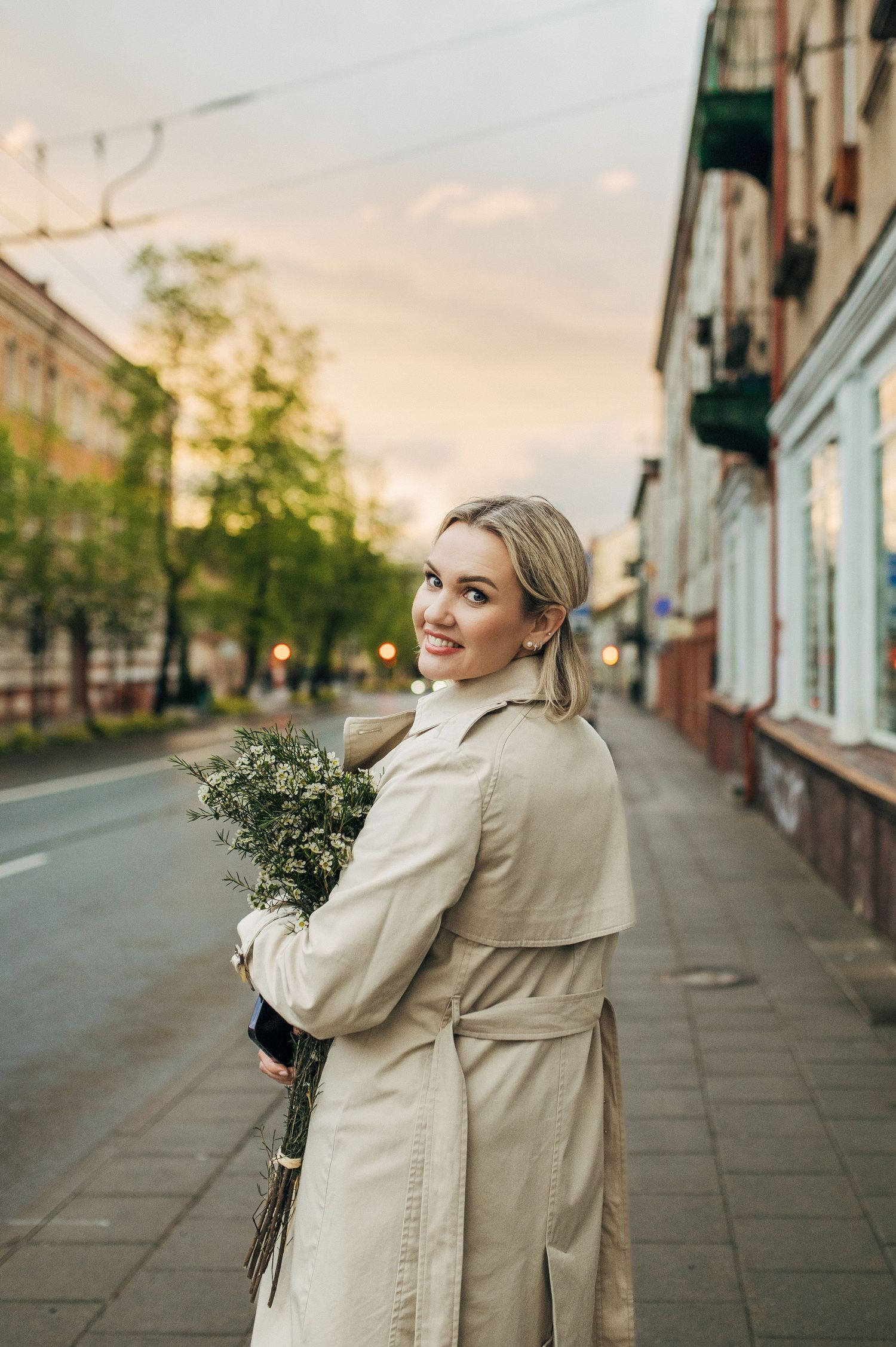 Candid street photography captures joyful moments in beige coat during golden hour.